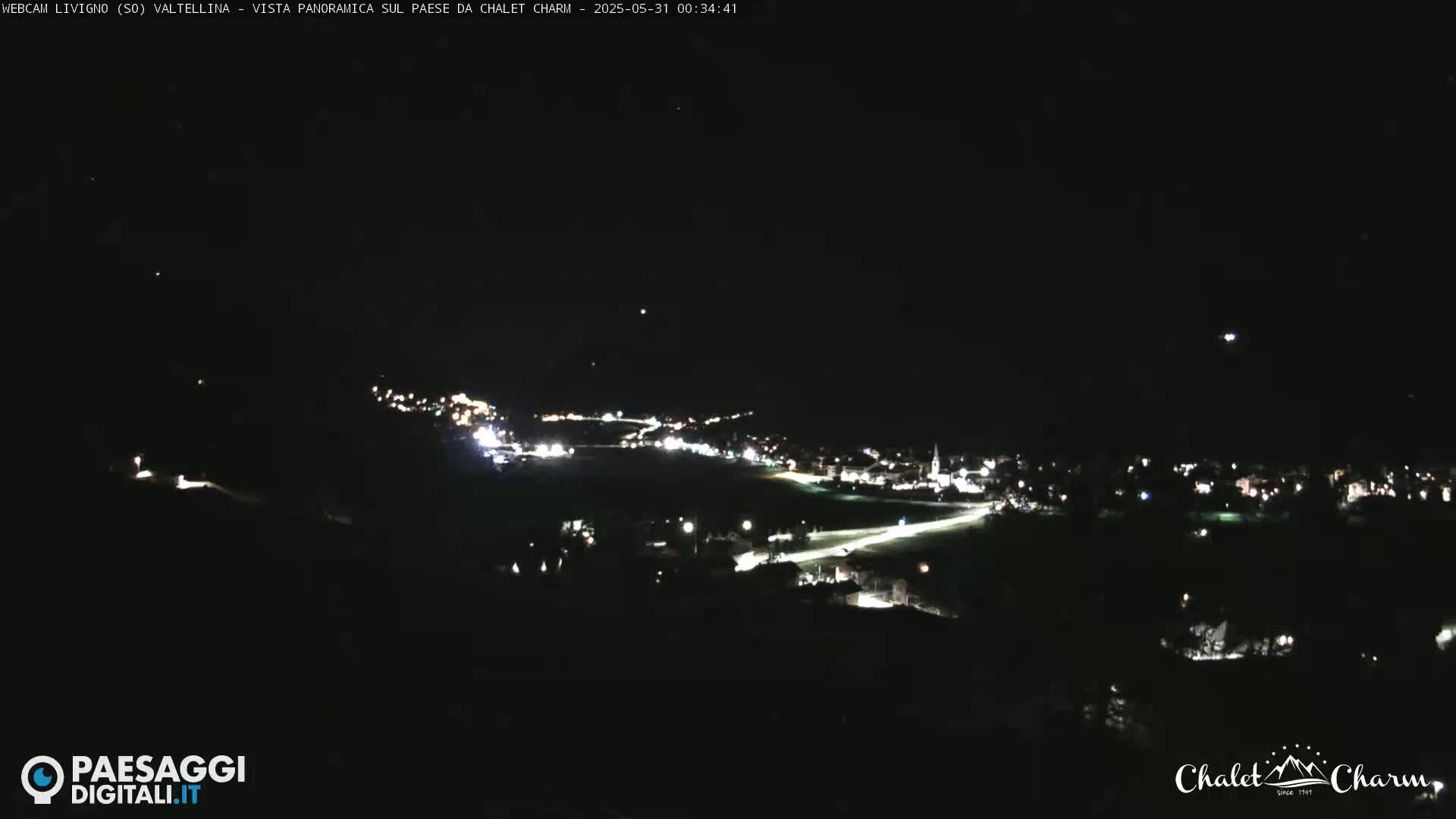 A nighttime, panoramic view of a town illuminated by lights, under a clear, dark sky.