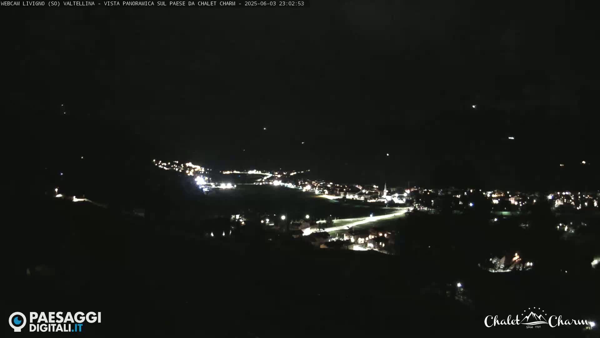 A nighttime, panoramic view of a small town illuminated by scattered lights.