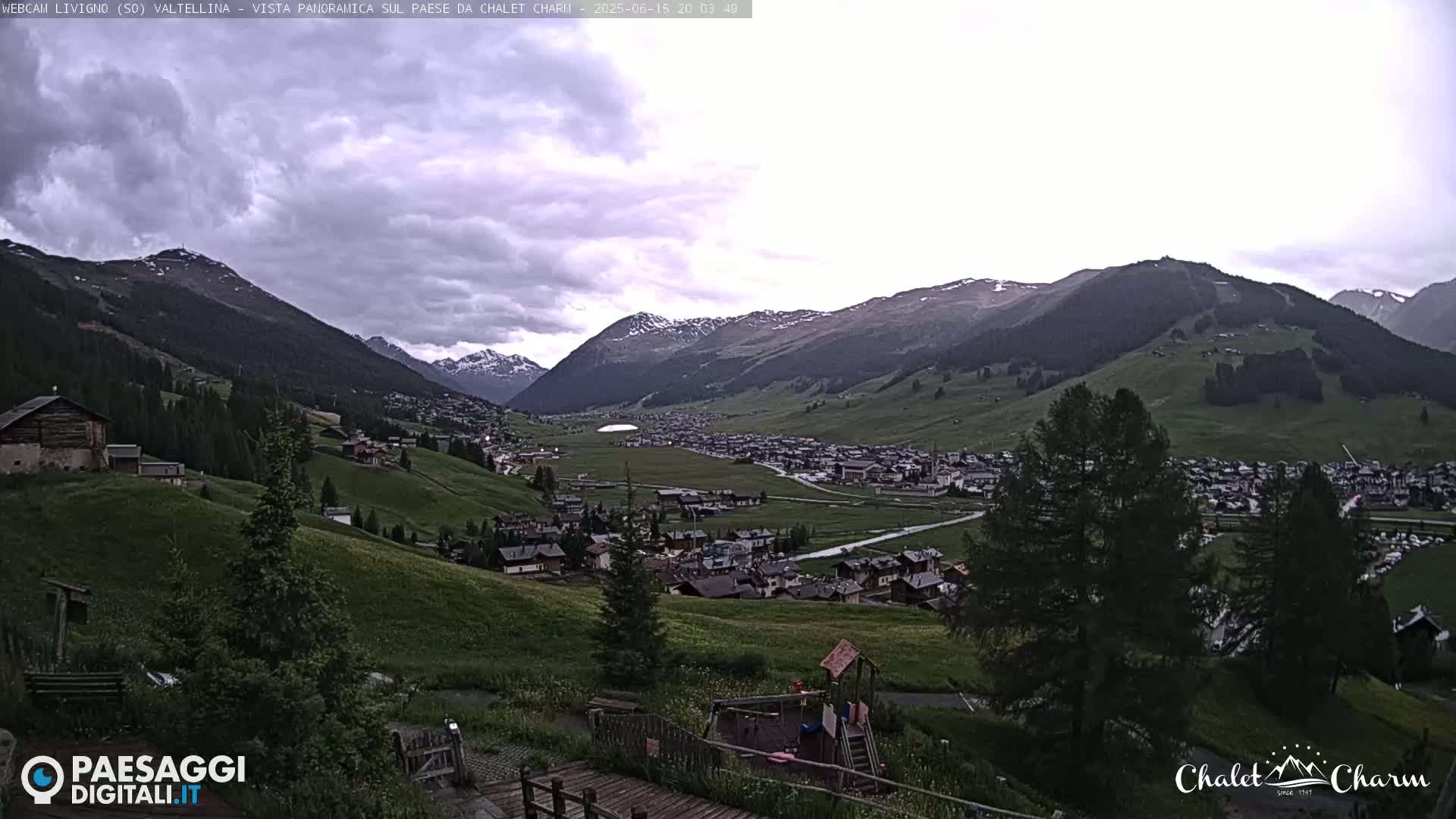 A panoramic view of a town nestled in a valley between mountains under an overcast sky.