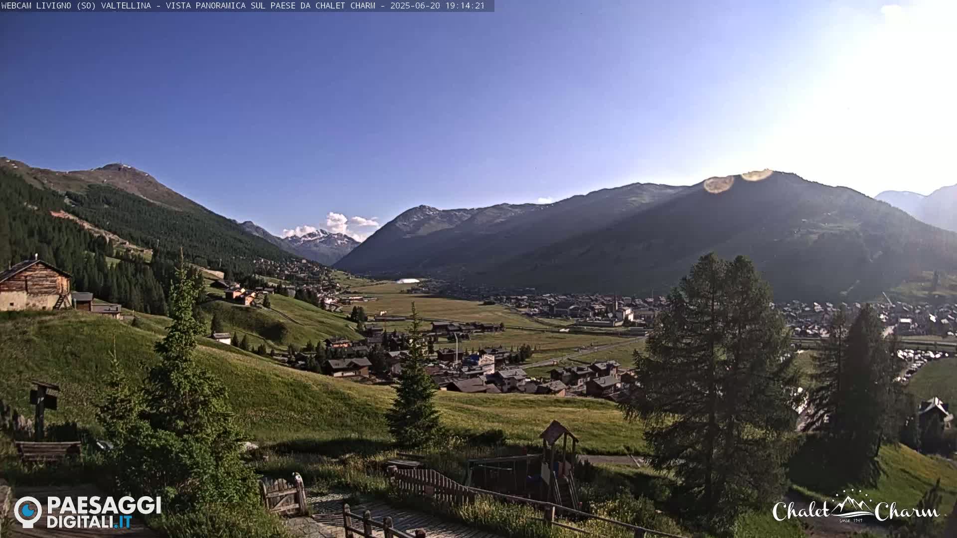 A sunny, panoramic view of a village nestled in a valley between mountains.