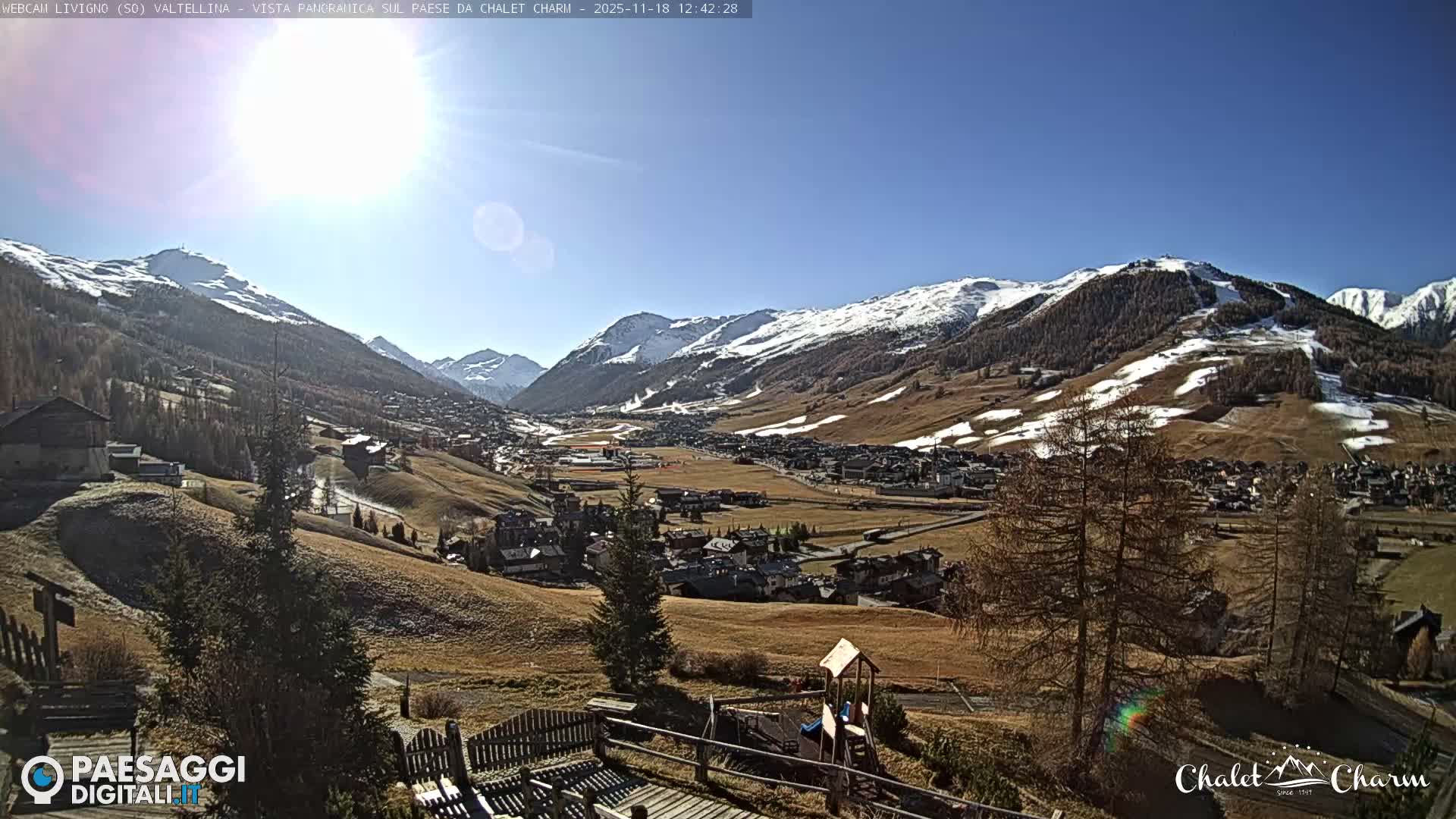 A panoramic nighttime view reveals a sprawling town or village illuminated by numerous artificial lights across a dark landscape under a clear sky.