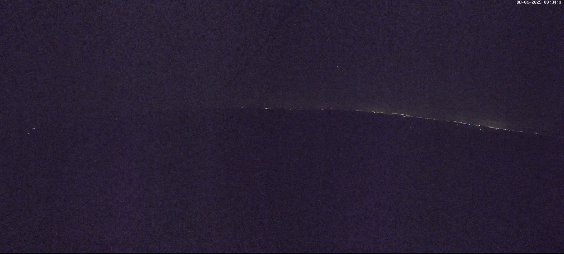 A distant line of lights is visible on a dark, nighttime horizon.