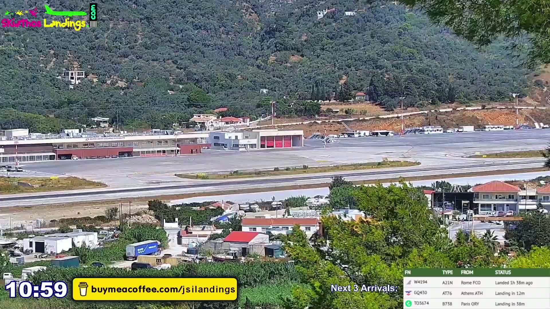 An airport terminal and surrounding area are shown on a sunny day, with hills in the background.