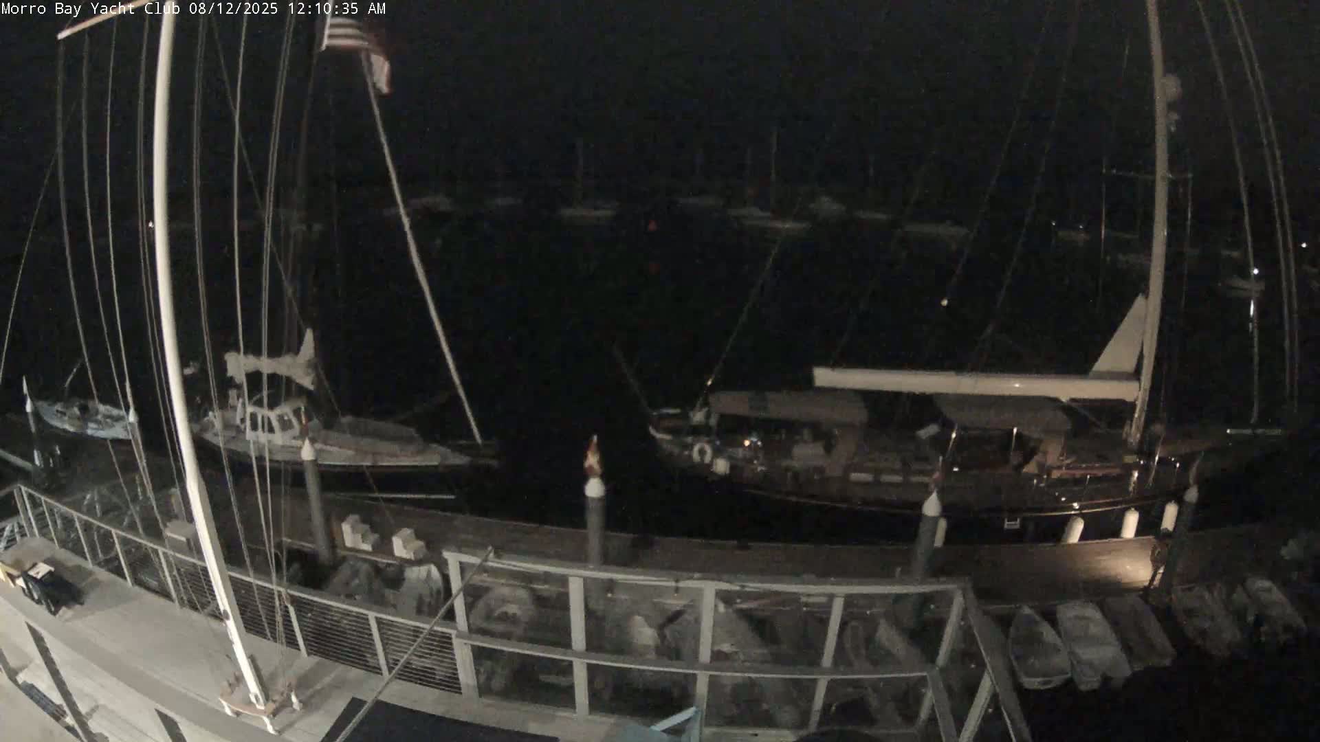 A nighttime view of a marina with numerous boats docked, under a dark sky.