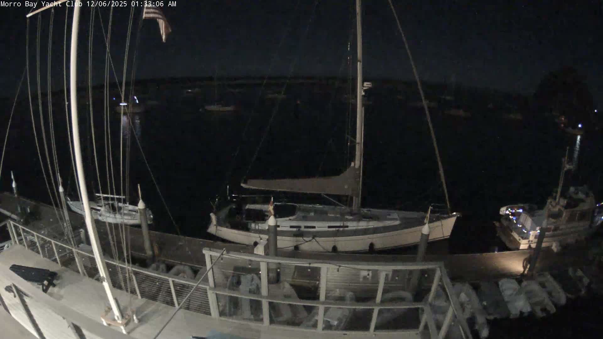 The image depicts a serene nighttime view of a marina with various boats docked and anchored in calm, dark waters under a clear sky.
