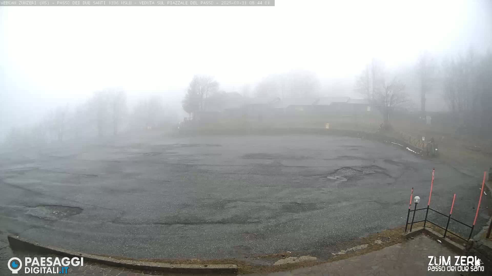 A foggy parking lot is visible, with a few buildings barely discernible in the distance.