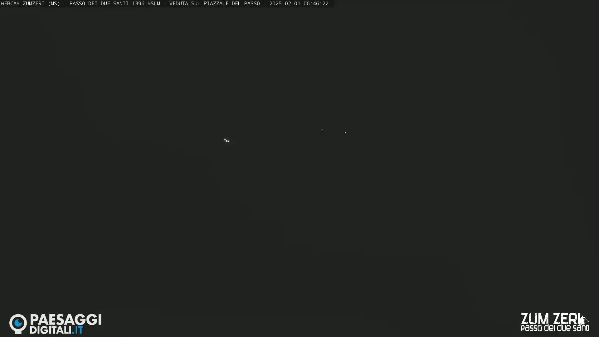 A dark nighttime scene shows several small, faint lights in the distance.