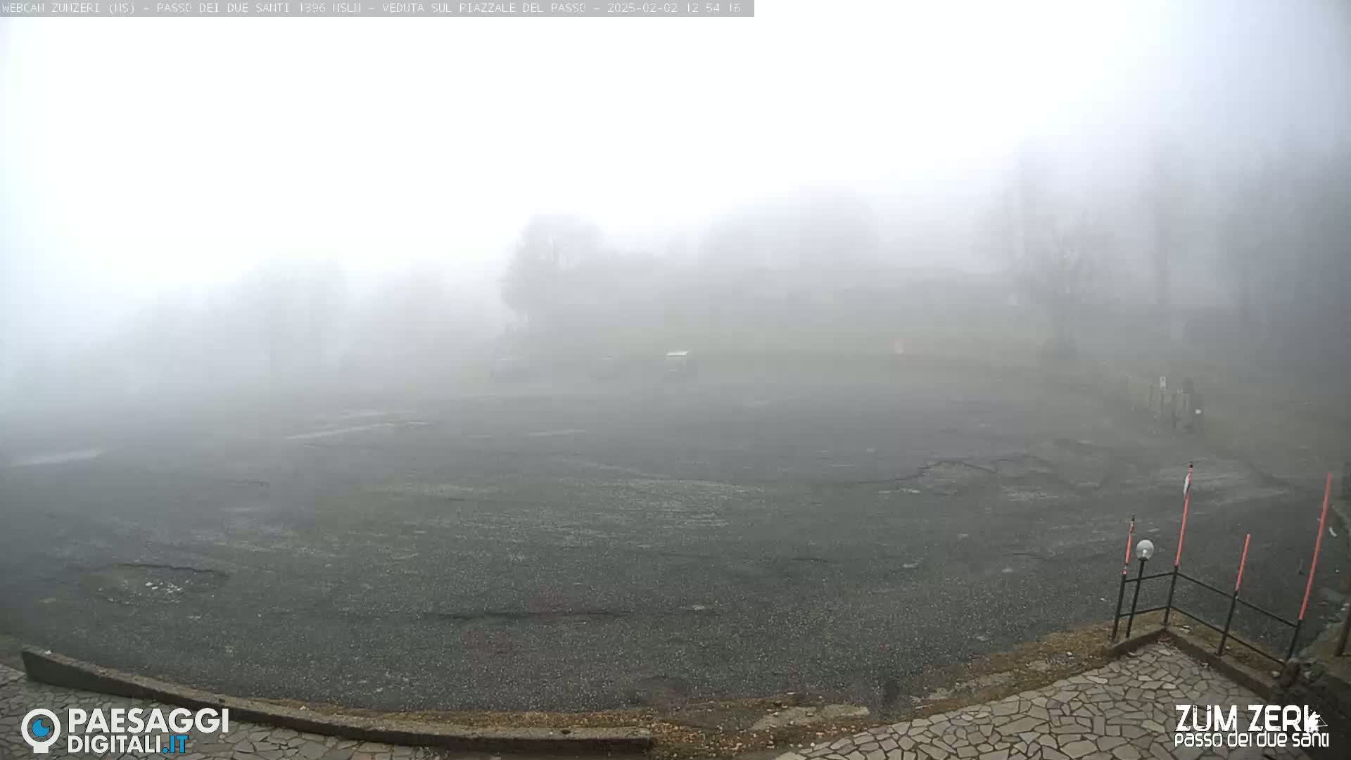 A foggy, empty asphalt lot is visible, bordered by a stone walkway and sparsely visible trees in the background.