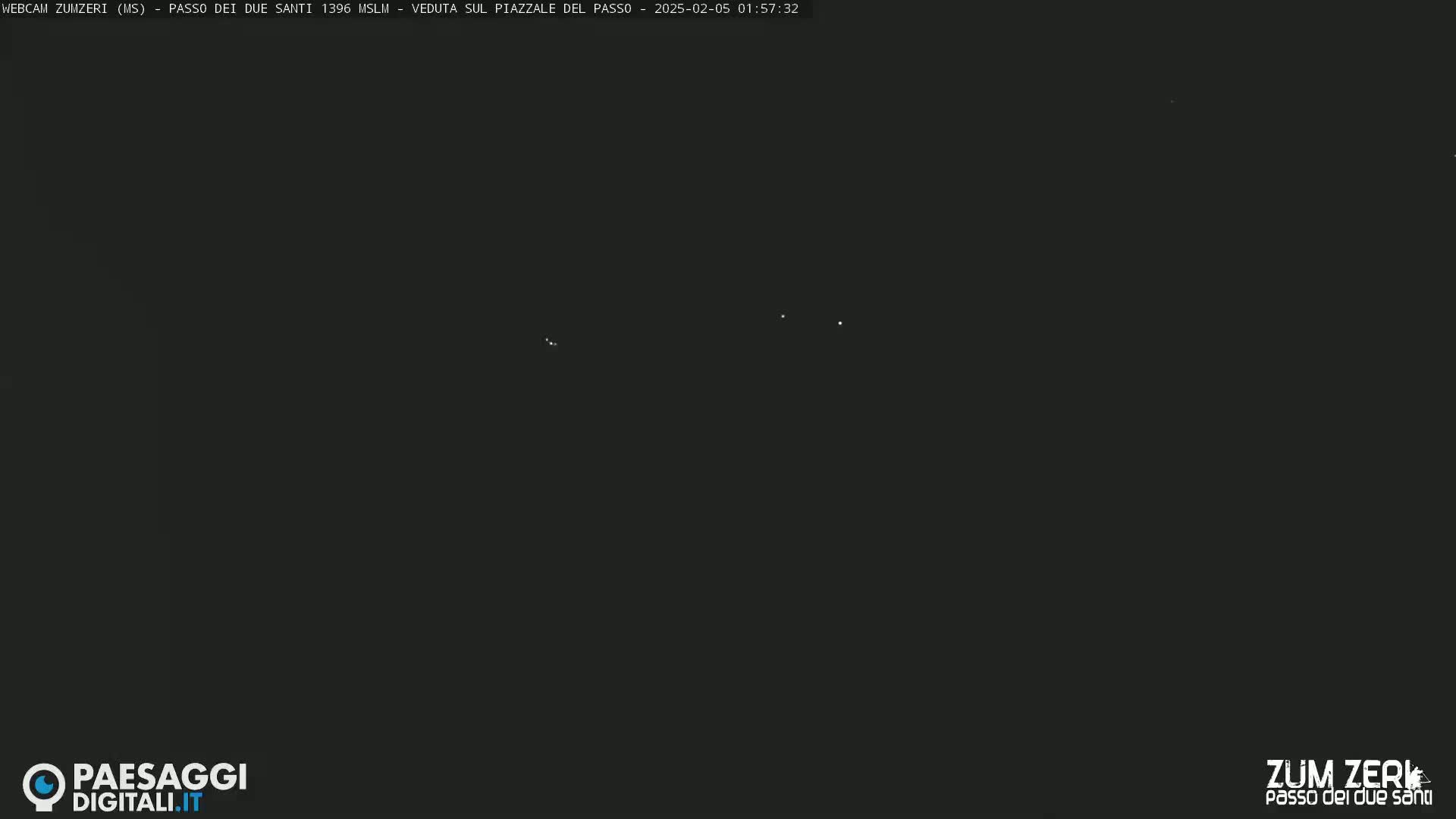 A dark nighttime scene shows a few very faint lights in the distance.