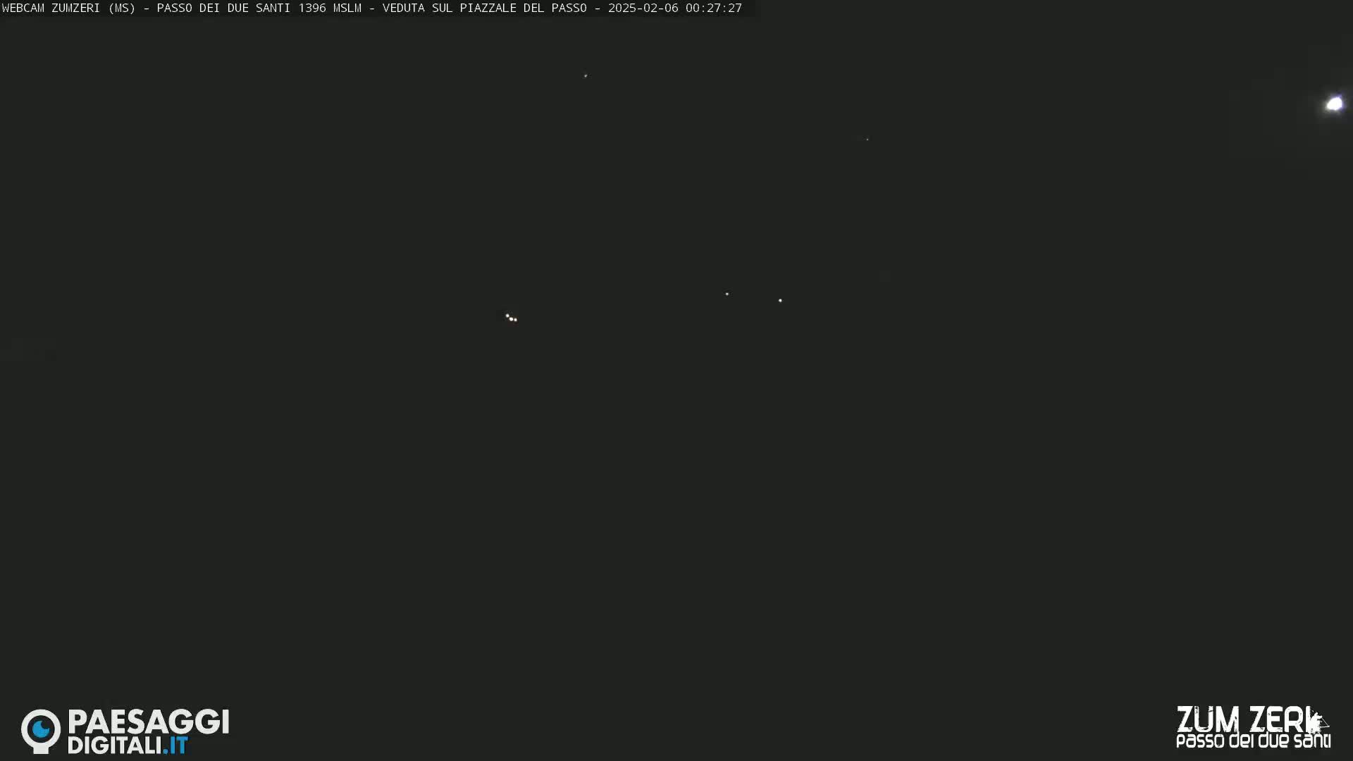 A nighttime, dark outdoor scene shows several faint lights in the sky, possibly stars or distant lights.
