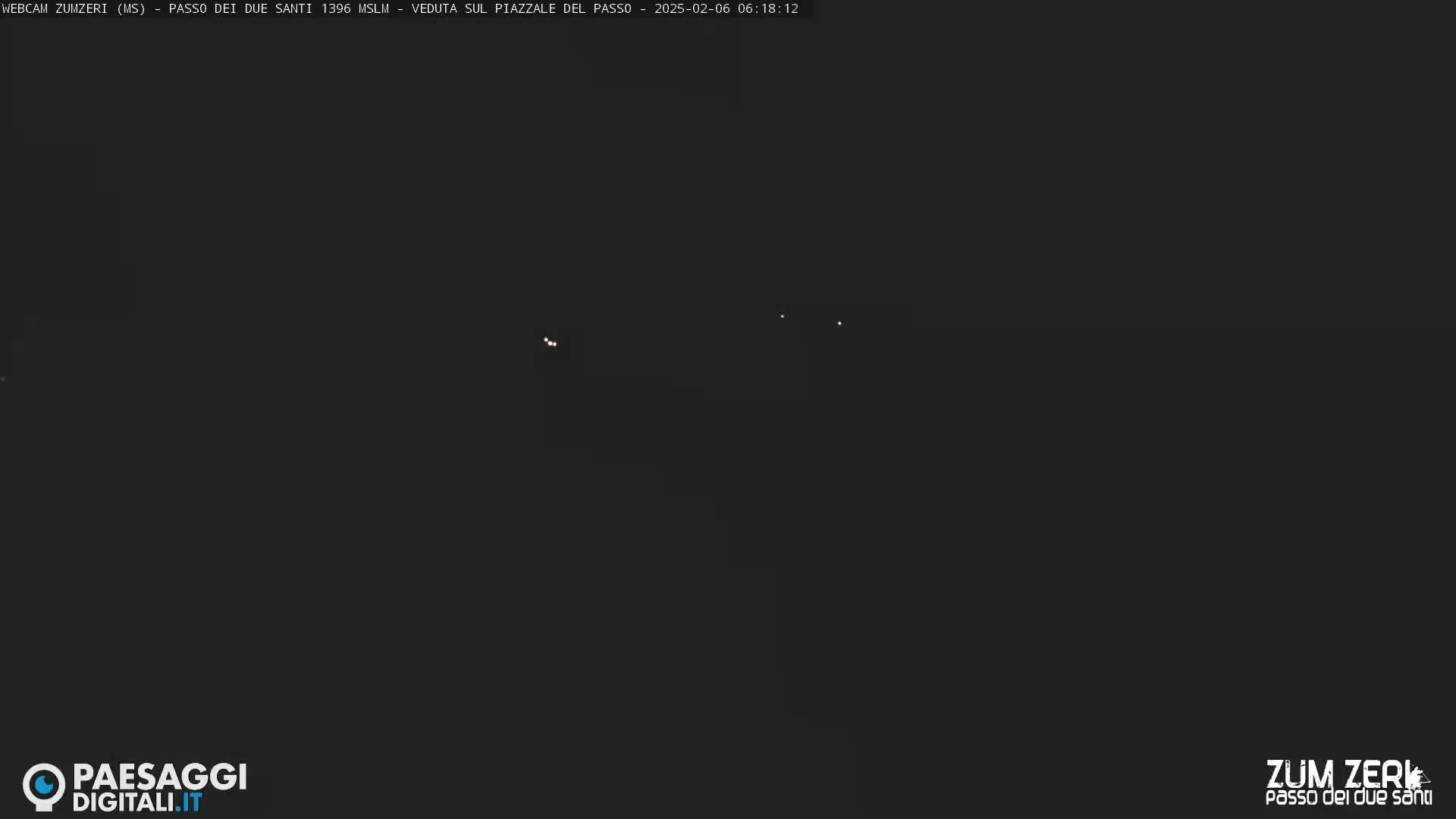 A dark, nighttime scene shows a few faint lights in the distance.