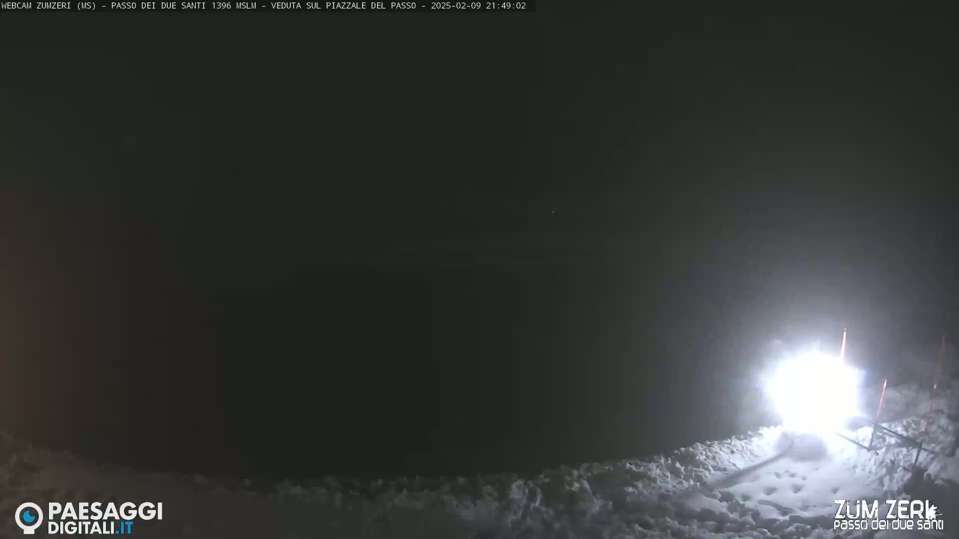 A bright light illuminates a snowy, nighttime scene.
