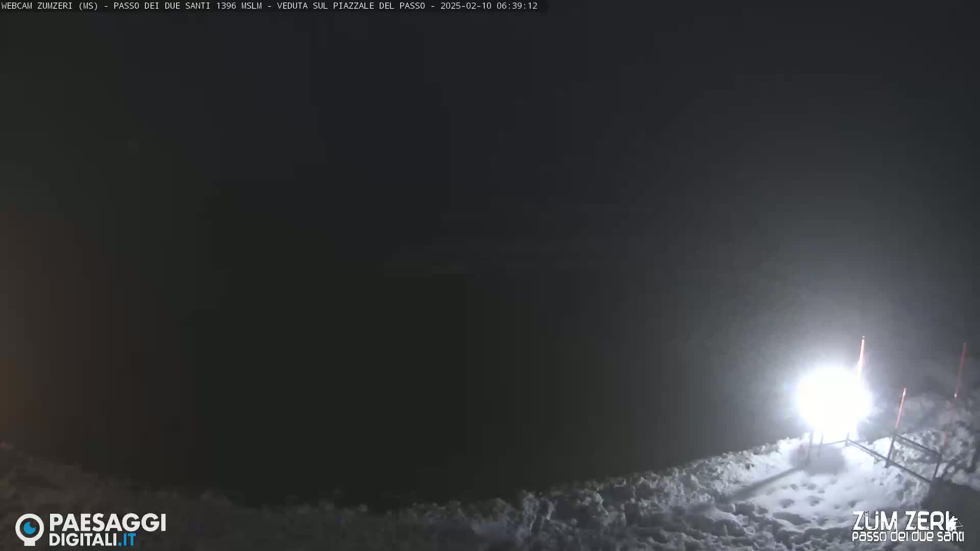 A bright light illuminates a snowy, nighttime scene.