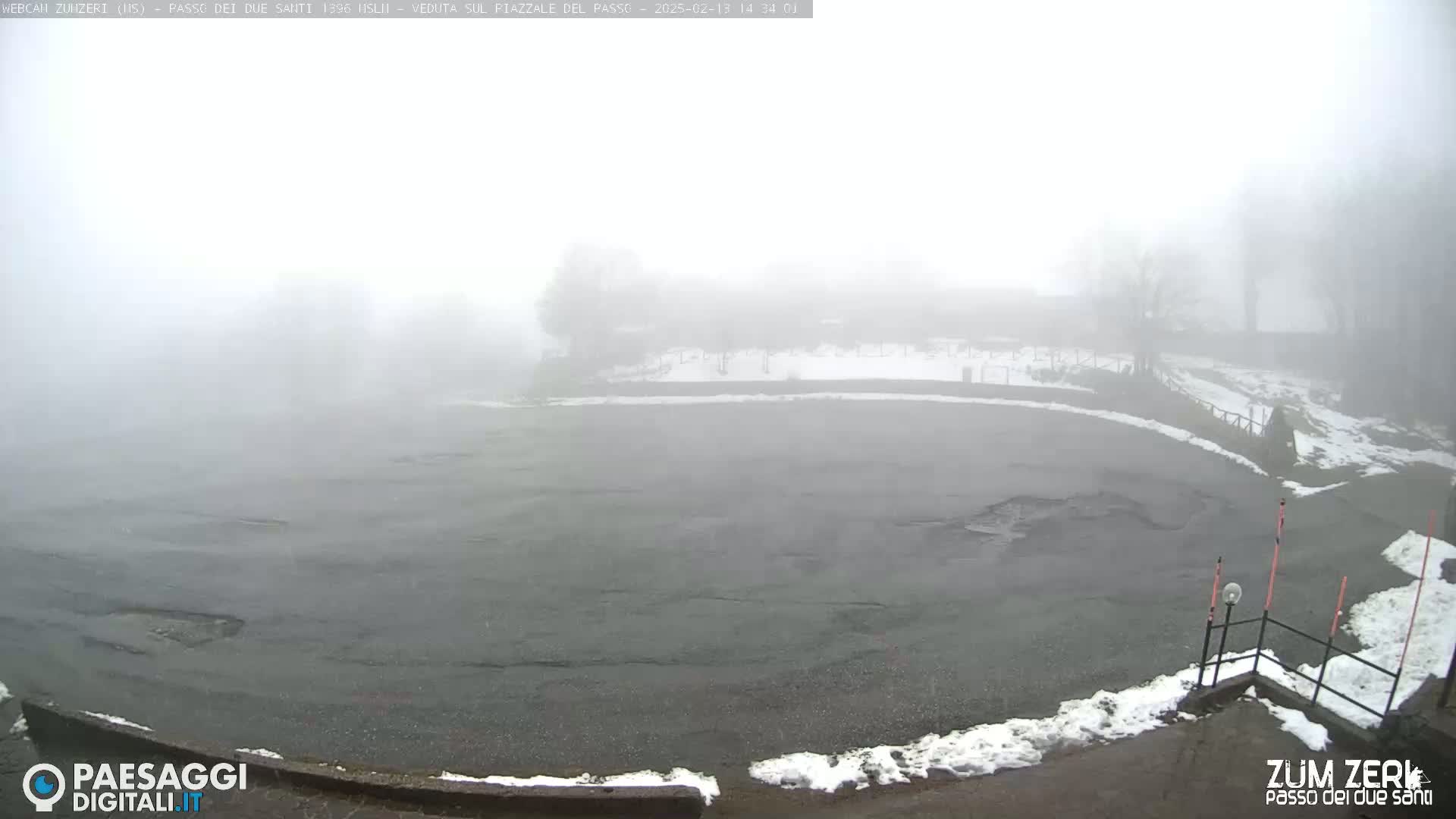 A foggy, snowy parking lot is visible, with a few trees barely seen in the distance.