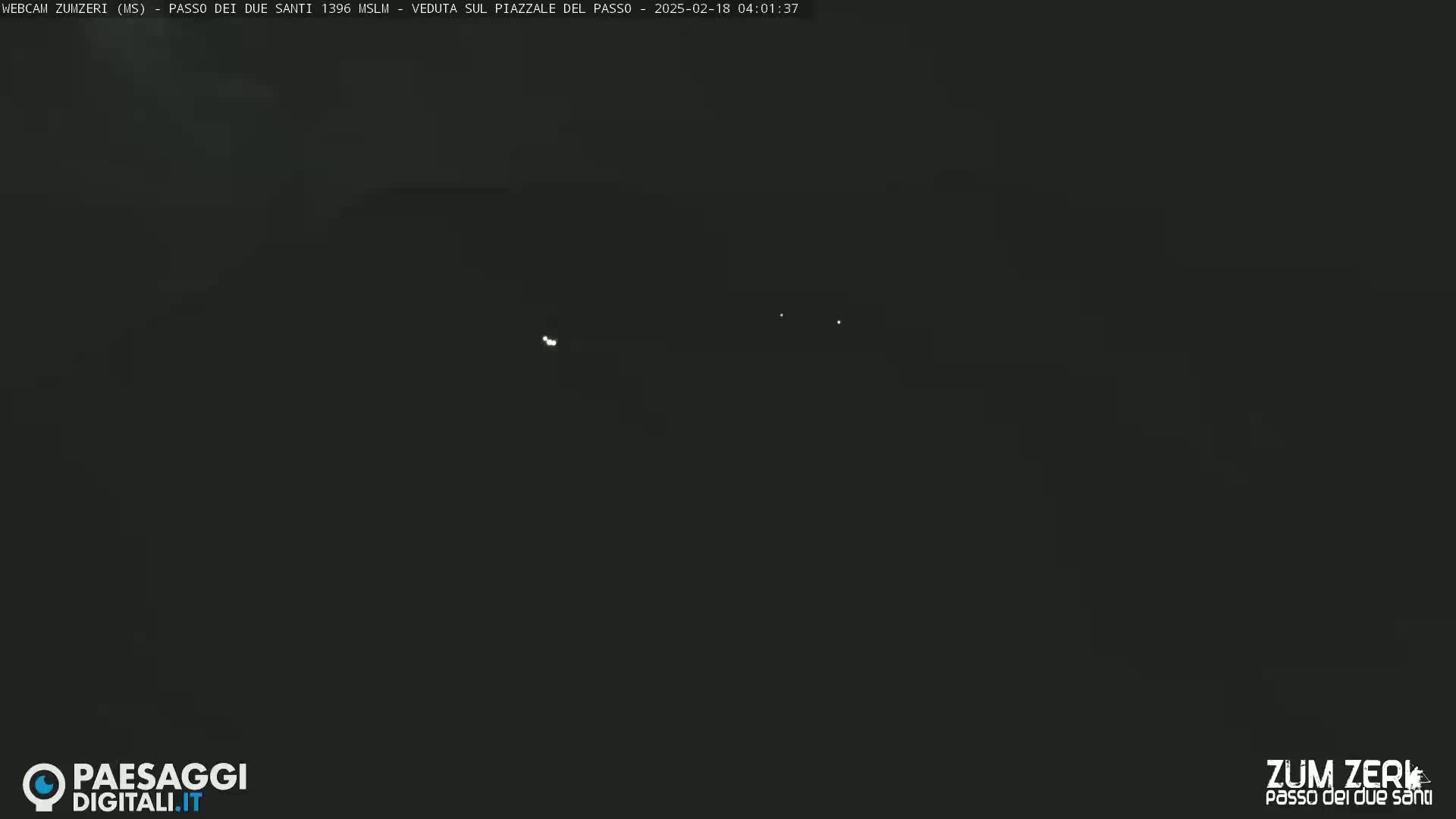 A dark, nighttime scene shows a few faint lights in the distance.
