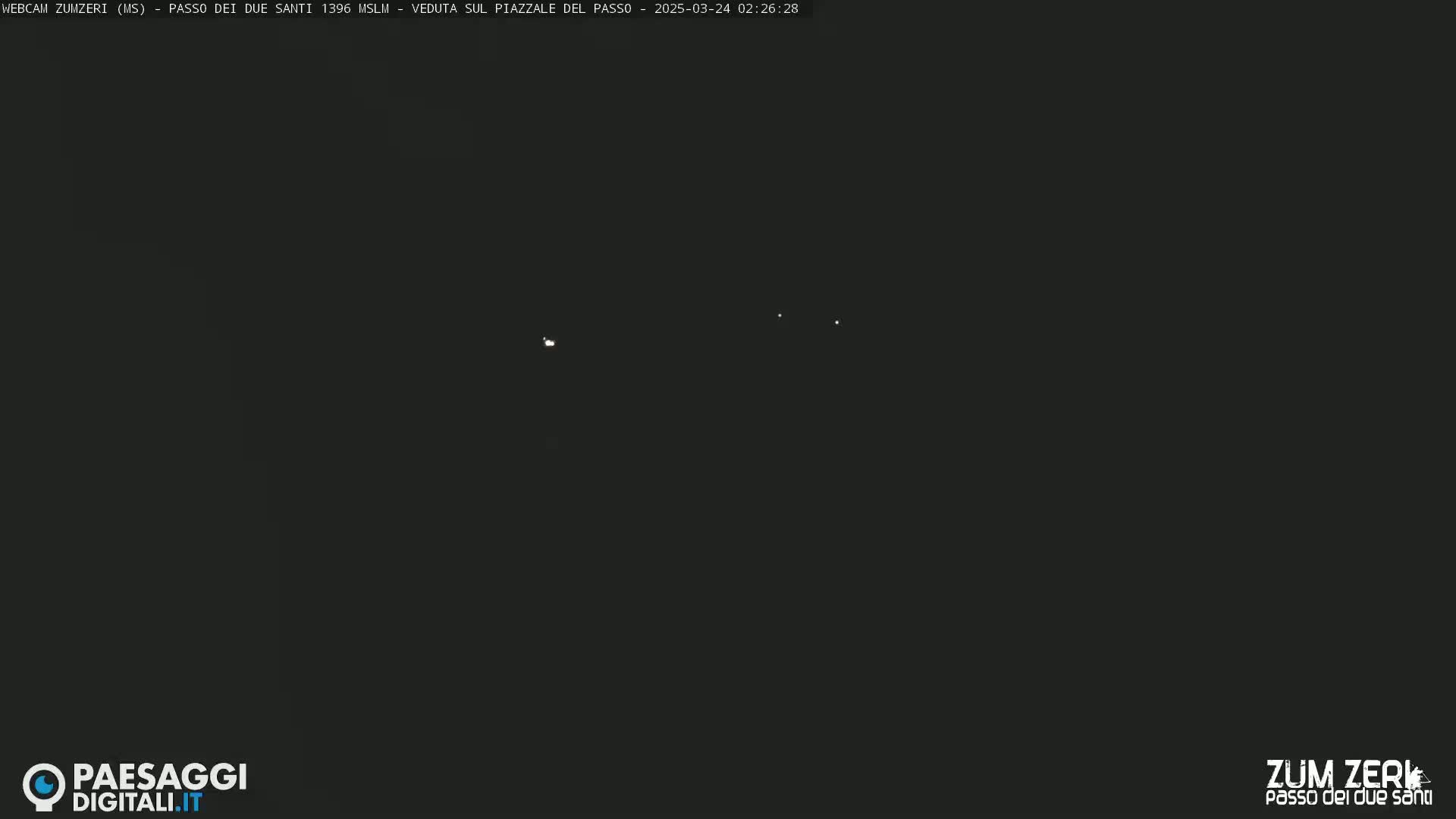 A dark, nighttime scene shows a few distant, faint lights.