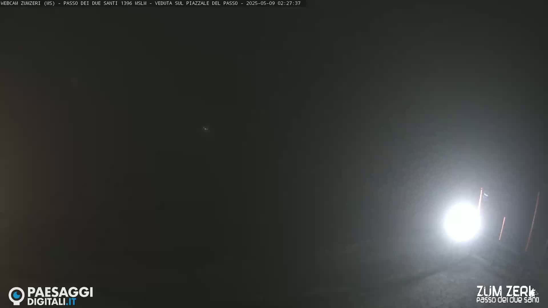 A bright light illuminates a foggy, dark scene at night.