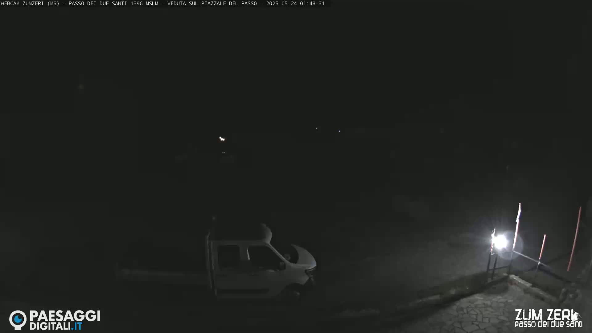 A white van is parked in a dark, outdoor area at night.