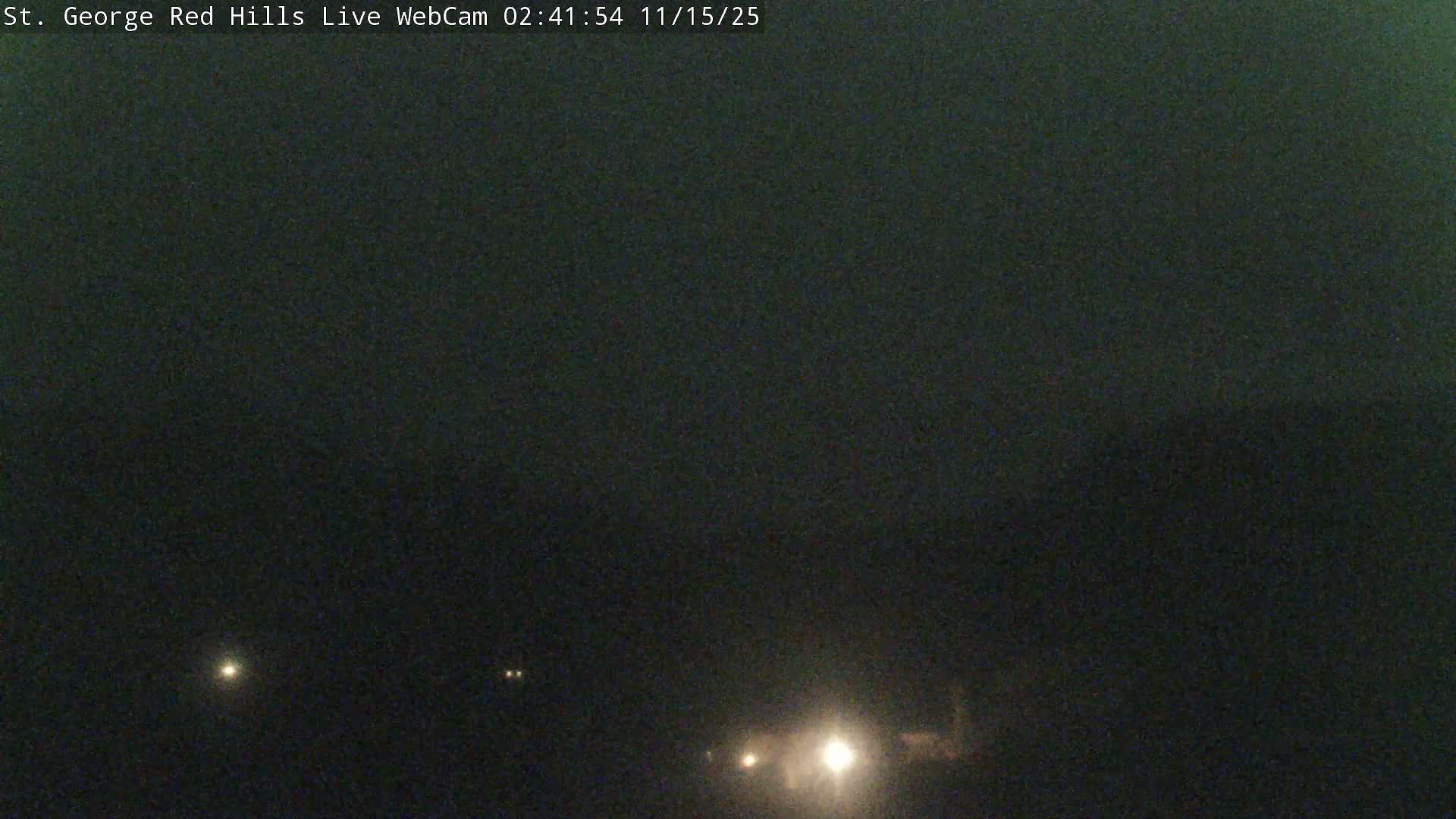 A dark, clear outdoor night scene features several bright lights in the distance, suggestive of vehicles on a road.