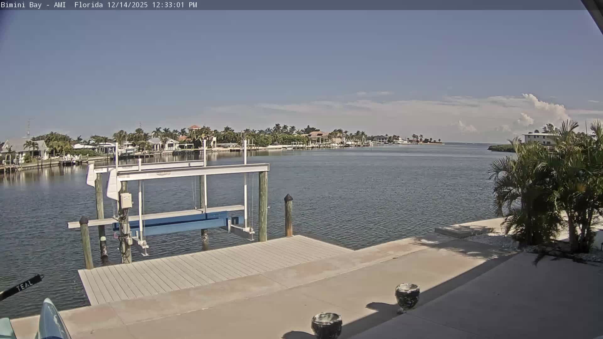 A boat dock stands on a dark, foggy bay or canal, with several bright lights piercing the thick mist in the distance.