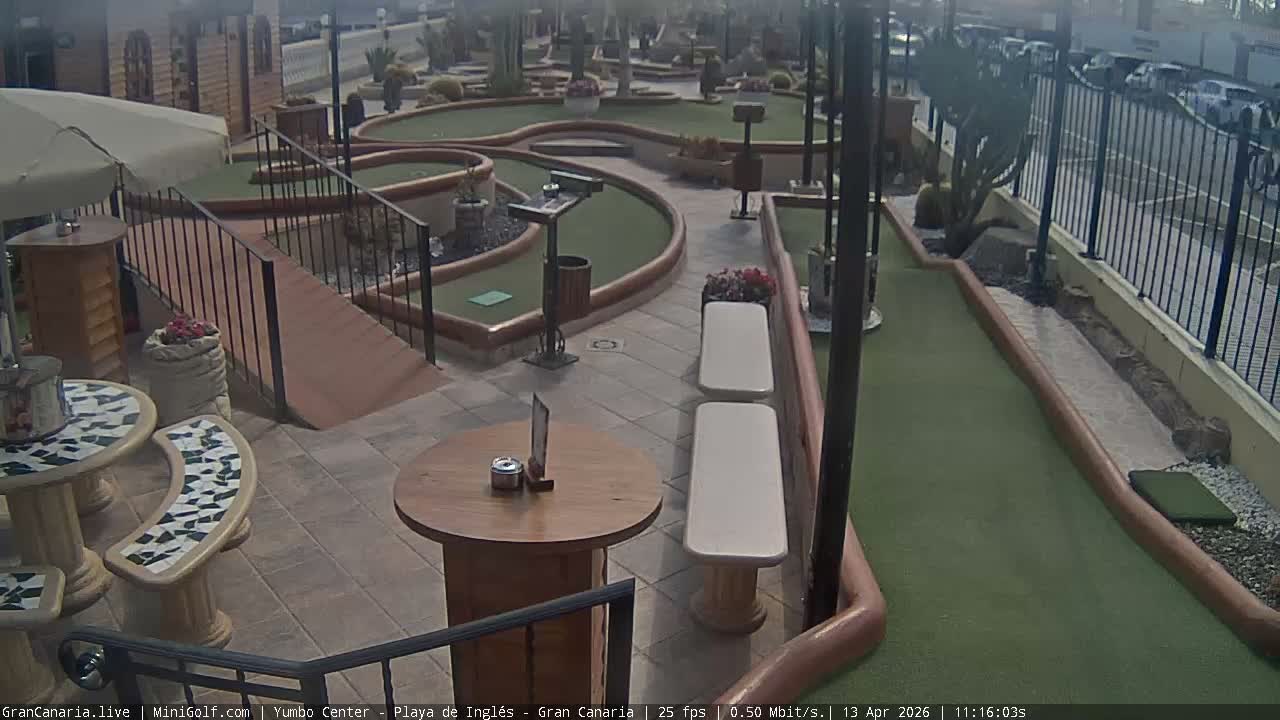 An outdoor mini-golf course is visible at night, brightly illuminated by a mix of colorful artificial lights under clear weather conditions.