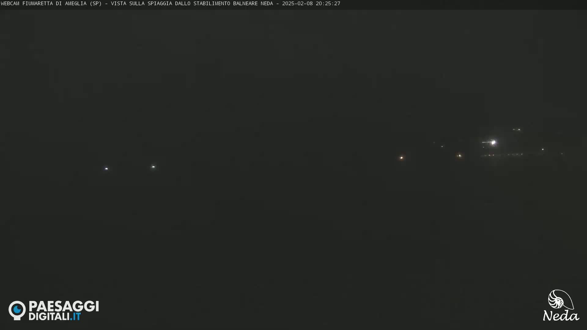 A dark, nighttime scene shows a few faint lights in the distance.