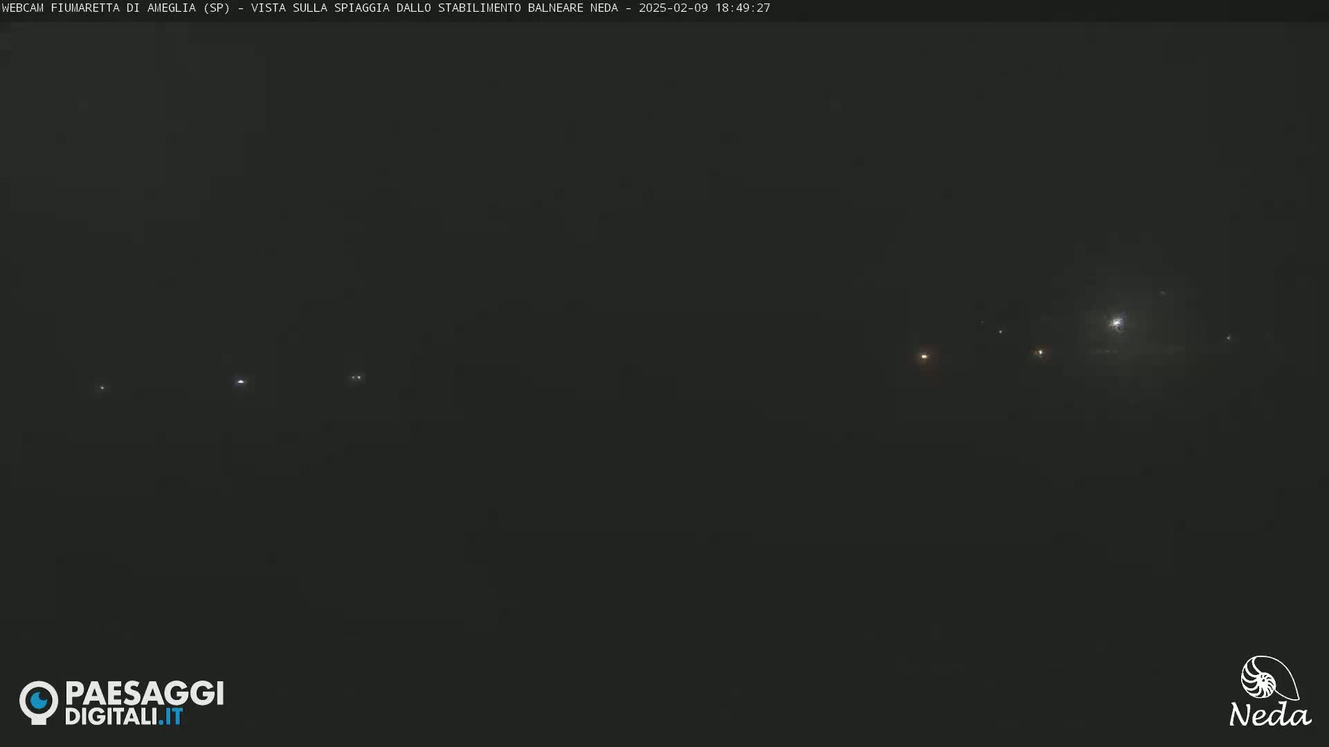 A nighttime, hazy view of faintly lit structures in the distance.