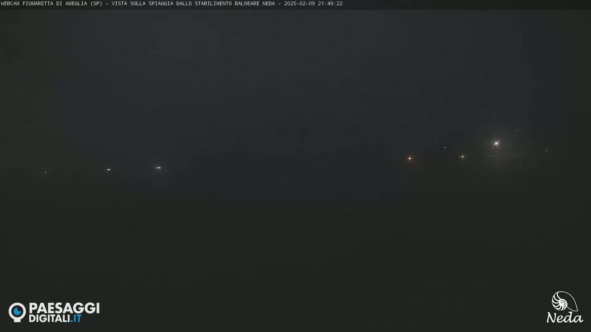 A dark, foggy night scene shows several faint lights in the distance.