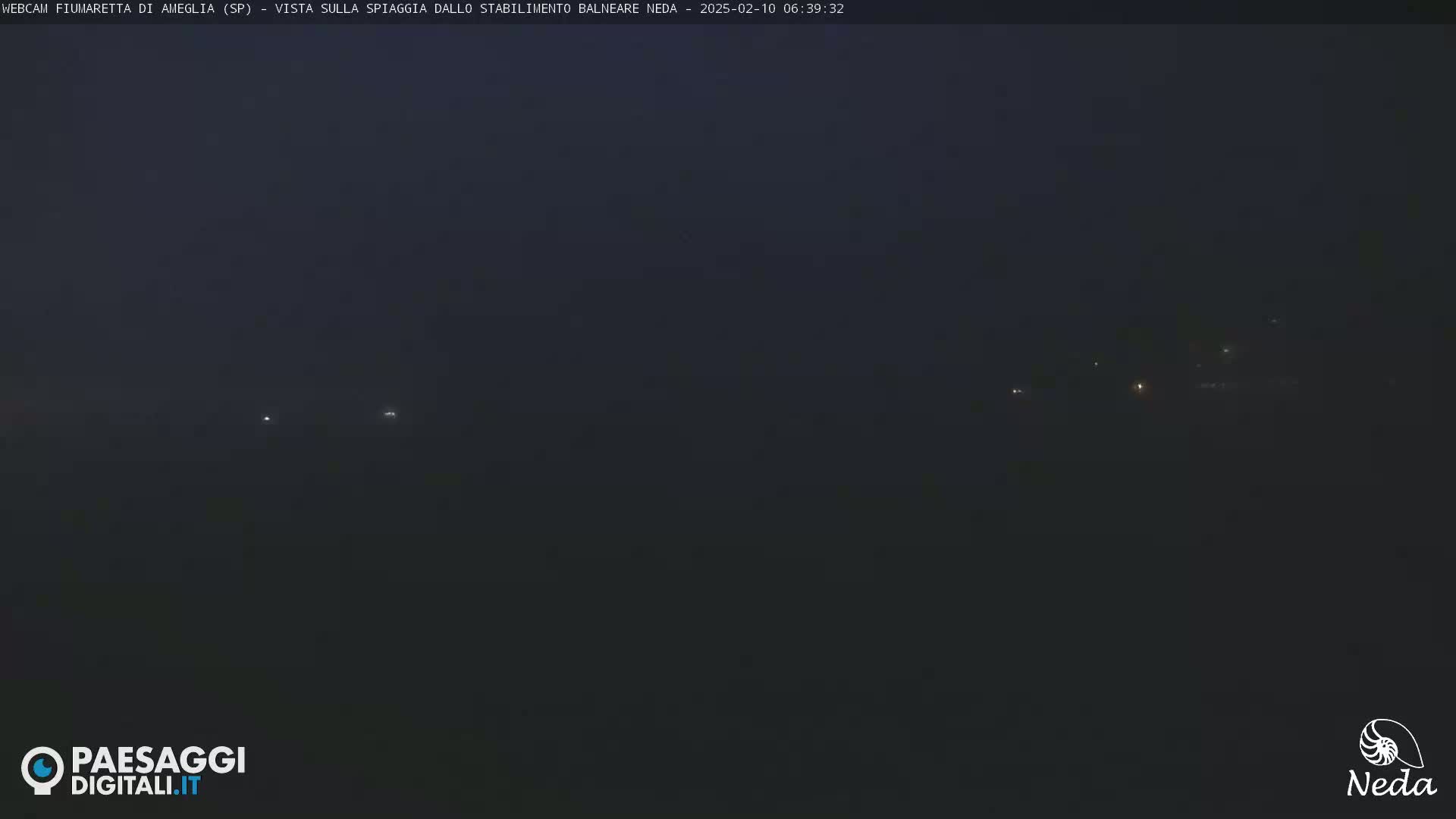 A dark, foggy scene at night shows a few distant lights.