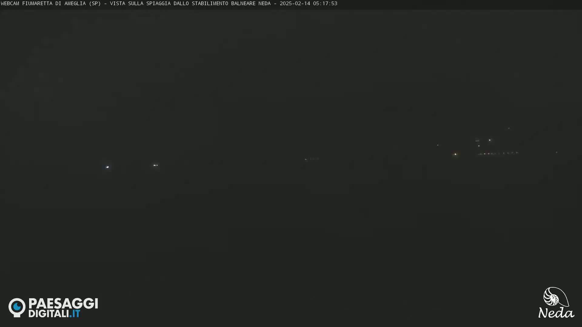 A dark, nighttime scene shows a few faint lights in the distance under a hazy or foggy sky.