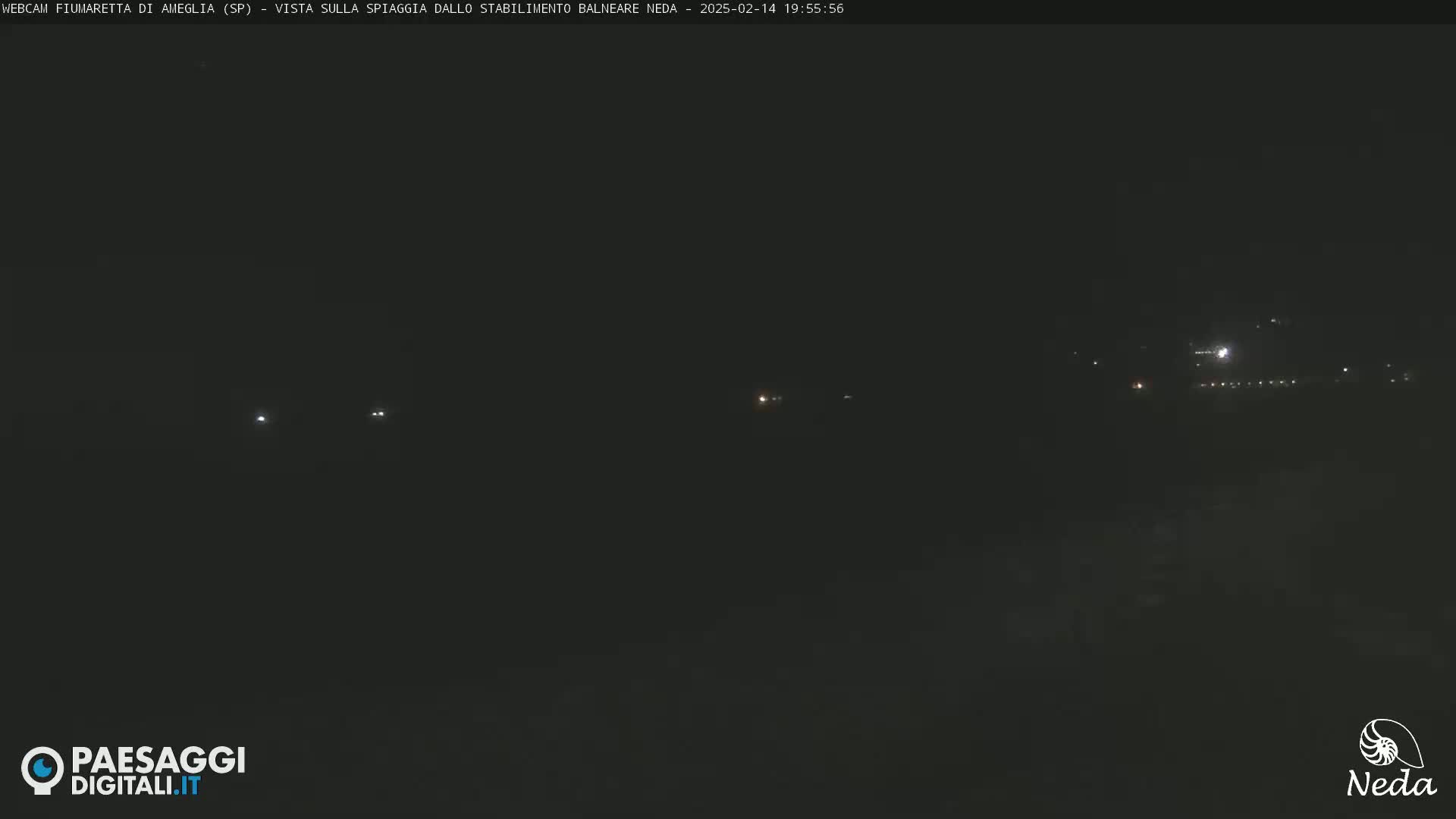 A nighttime, dark view of a distant shoreline with several small, faint lights visible.