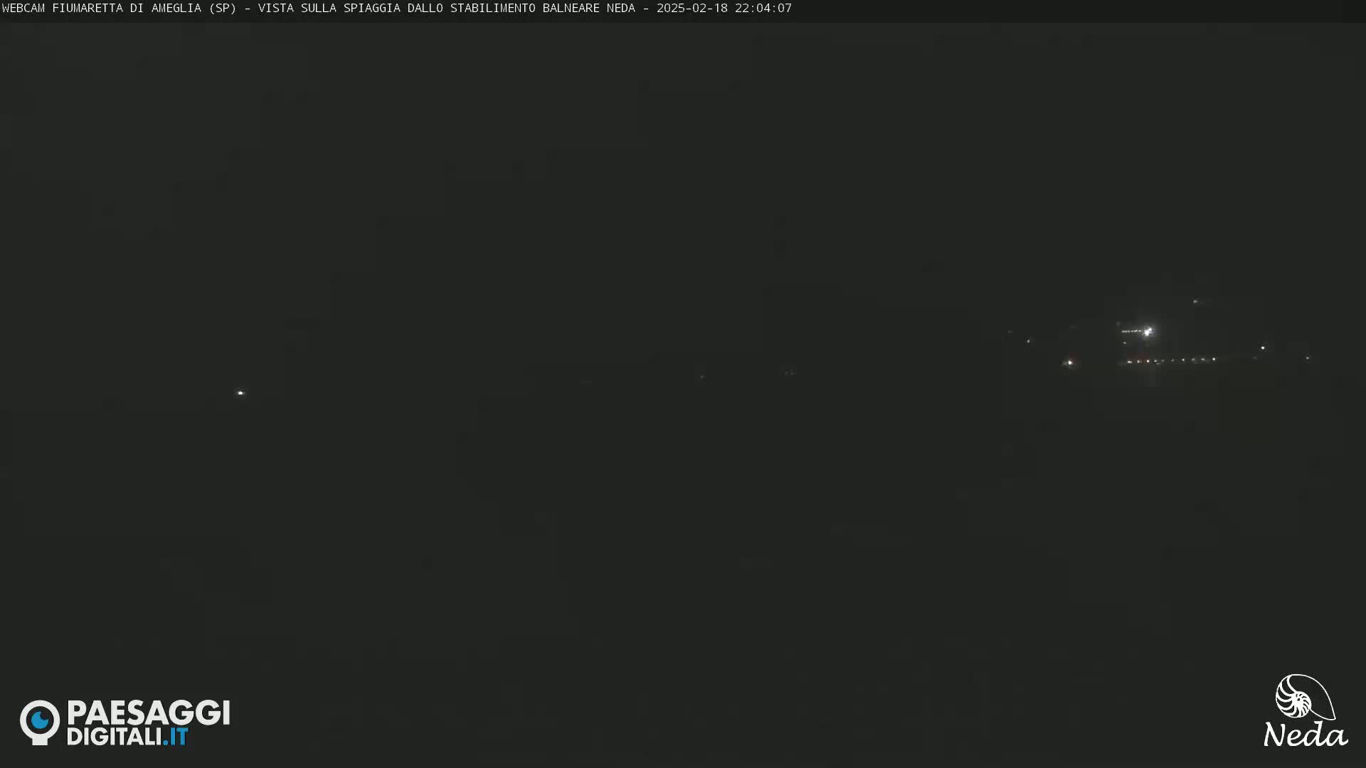 A dark, nighttime view of a dimly lit shoreline.