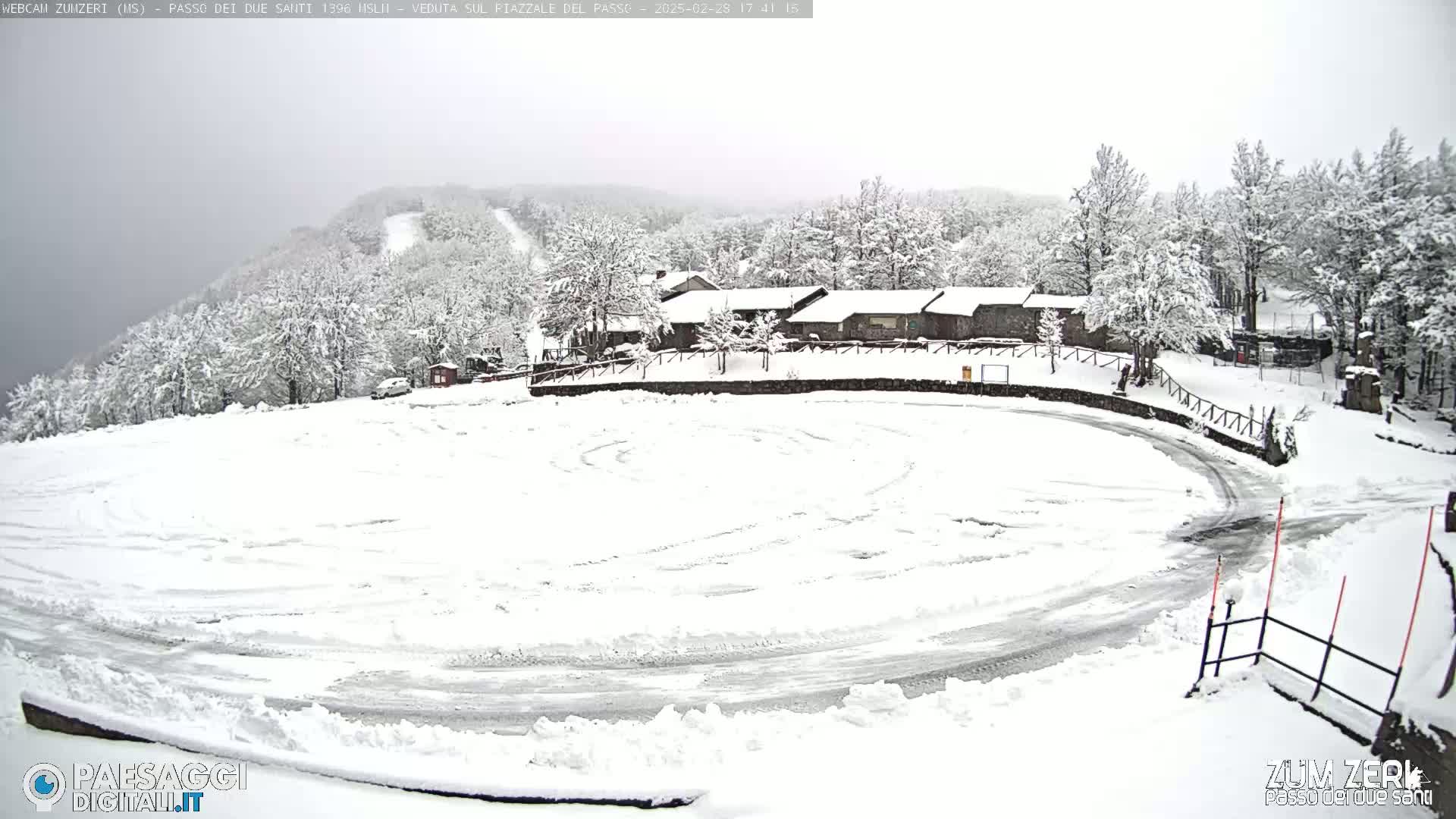 A snow-covered parking lot and surrounding snow-covered buildings and trees are visible under an overcast sky.