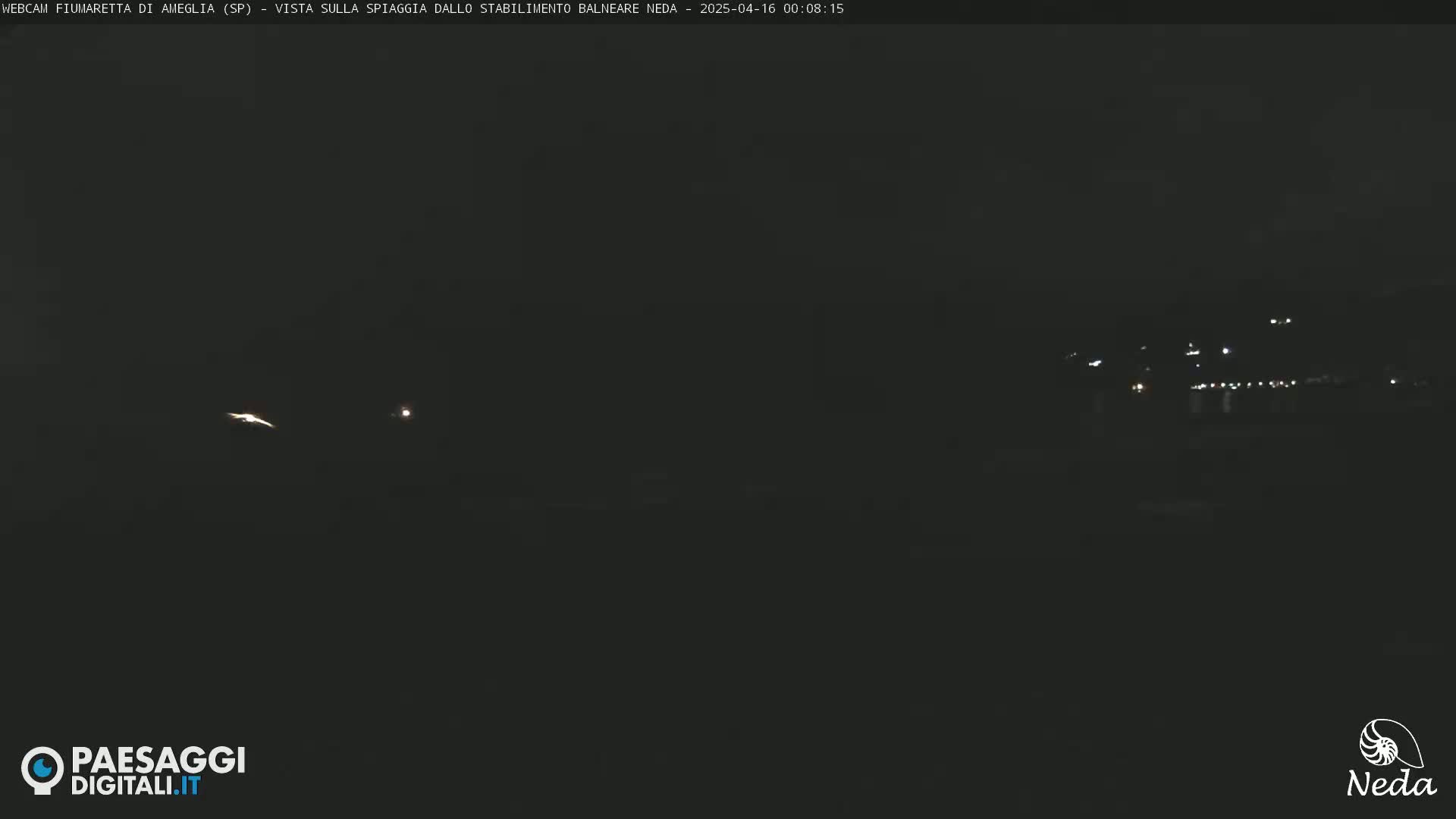 A dark, nighttime scene shows a distant line of lights across the water.