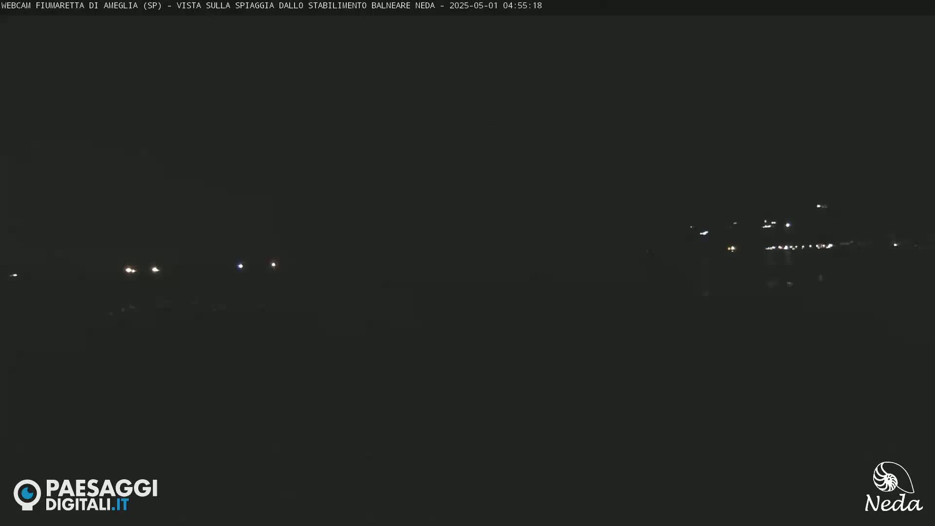 A dark nighttime scene shows a few distant lights on a hill across a dark expanse.