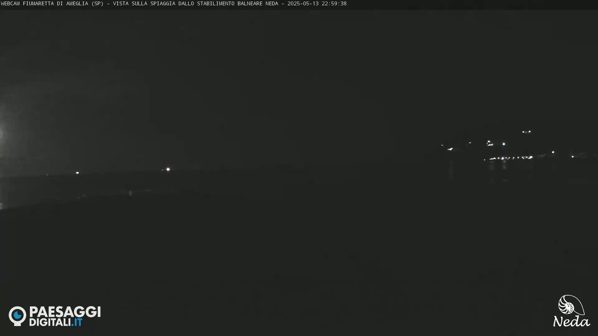 A nighttime, dark view of a distant, faintly lit shoreline.