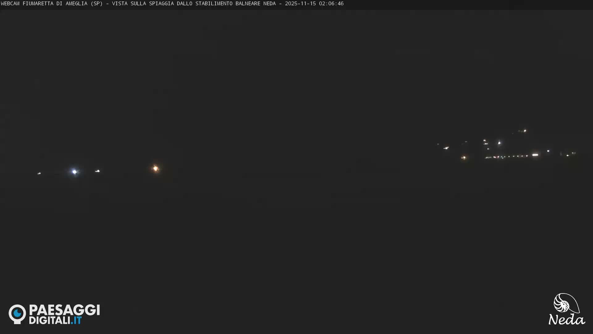 The image displays a dark outdoor night scene with scattered distant lights, likely from vehicles or structures, under clear weather conditions.