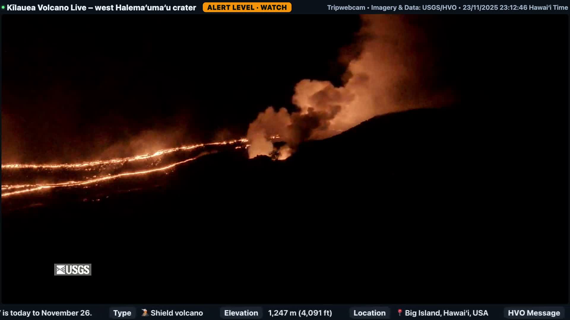 Under a clear night sky, molten orange lava flows snake across dark volcanic slopes, illuminated by the fiery eruption and rising plumes of smoke.