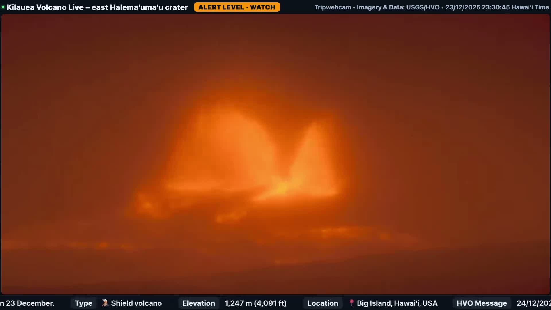 At night, a dark volcanic landscape is illuminated by brightly glowing areas on the left, with white and gray steam plumes rising and drifting across the terrain under clear sky conditions.