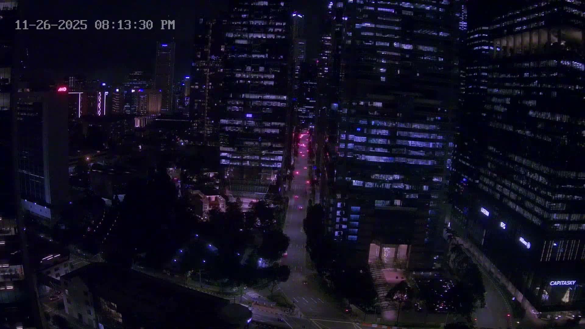 An elevated view reveals a dense city with towering modern skyscrapers flanking a busy street, interspersed with lower buildings and green parks, all beneath an overcast sky.