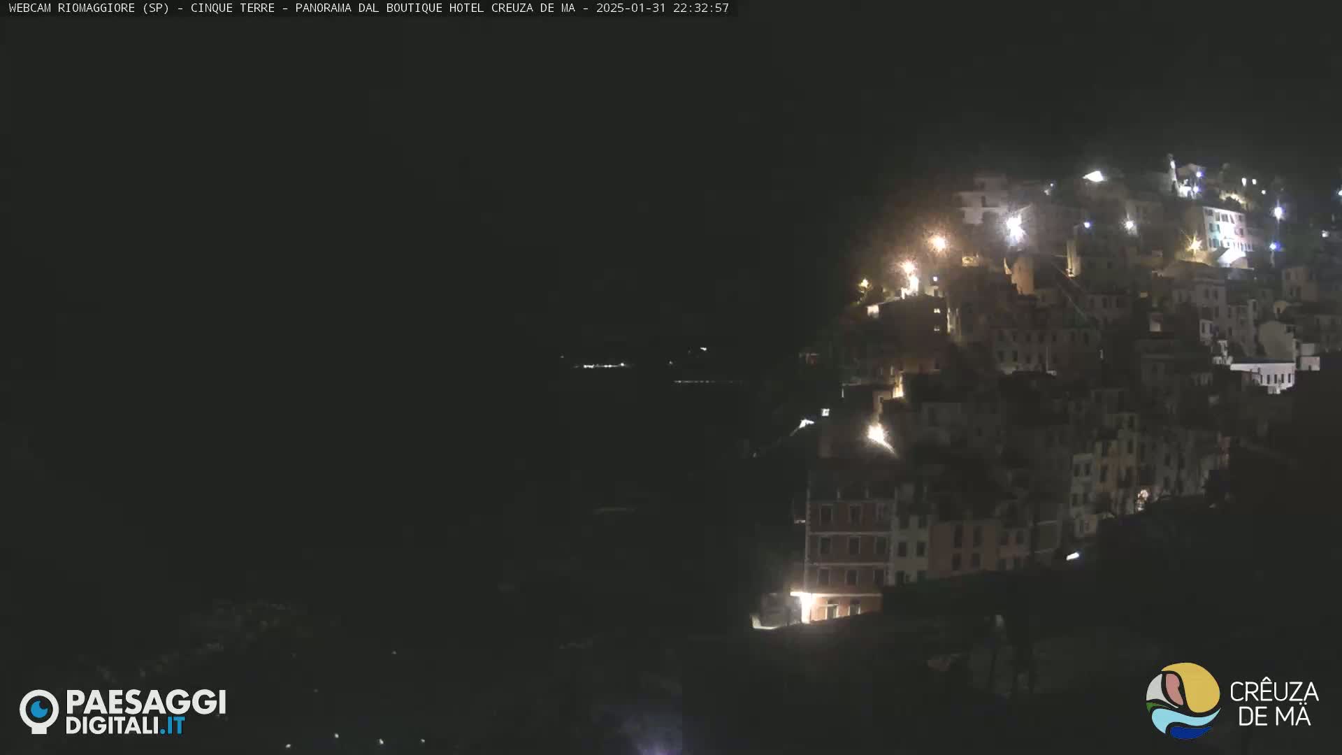 A nighttime view of a hillside town illuminated by scattered lights.