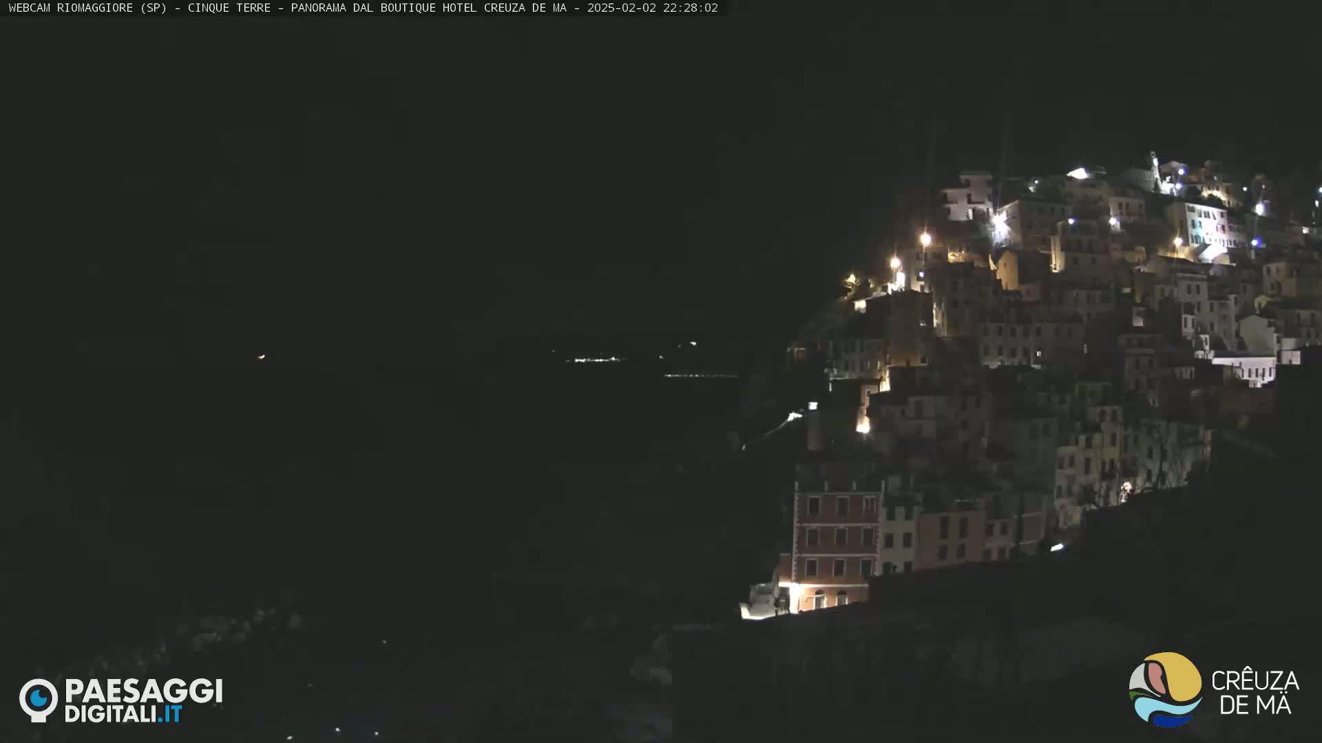 A hillside town is illuminated at night under a dark sky.