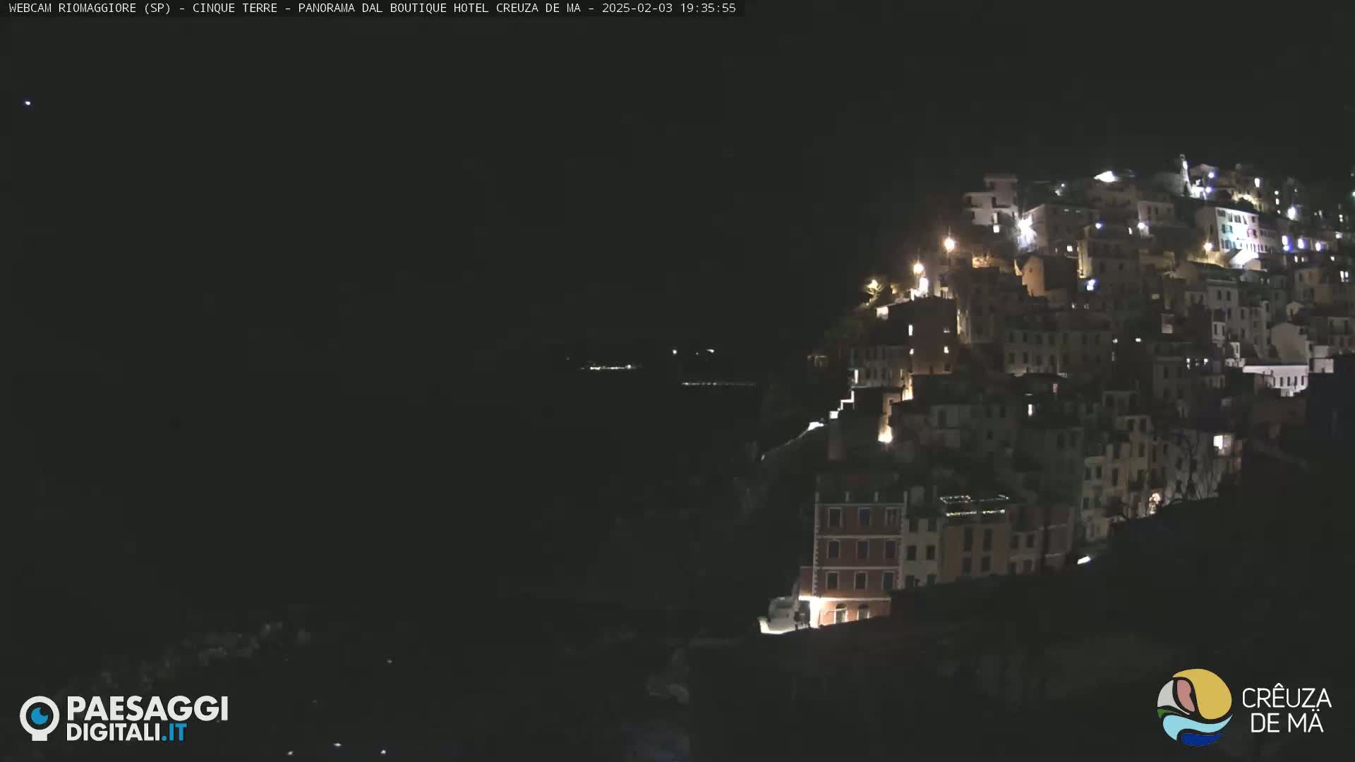A hillside village is illuminated at night.