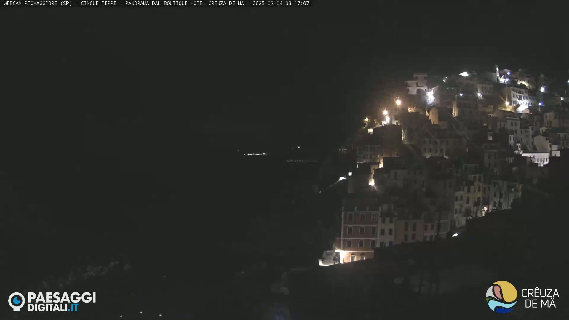 A hillside village is illuminated at night.