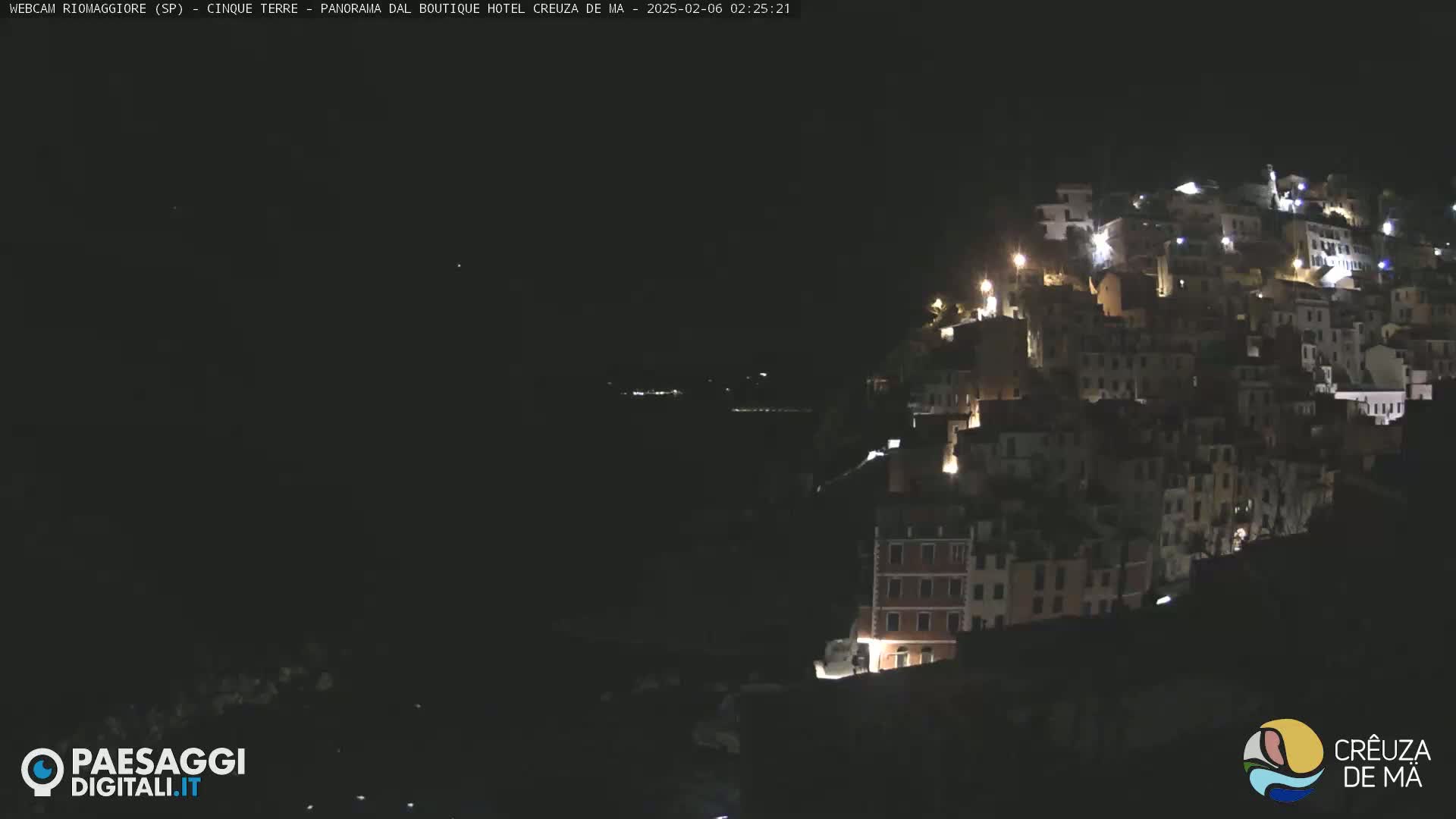 A nighttime view of a hillside town illuminated by scattered lights.