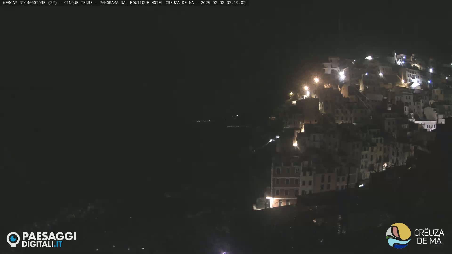 A hillside village is illuminated at night.