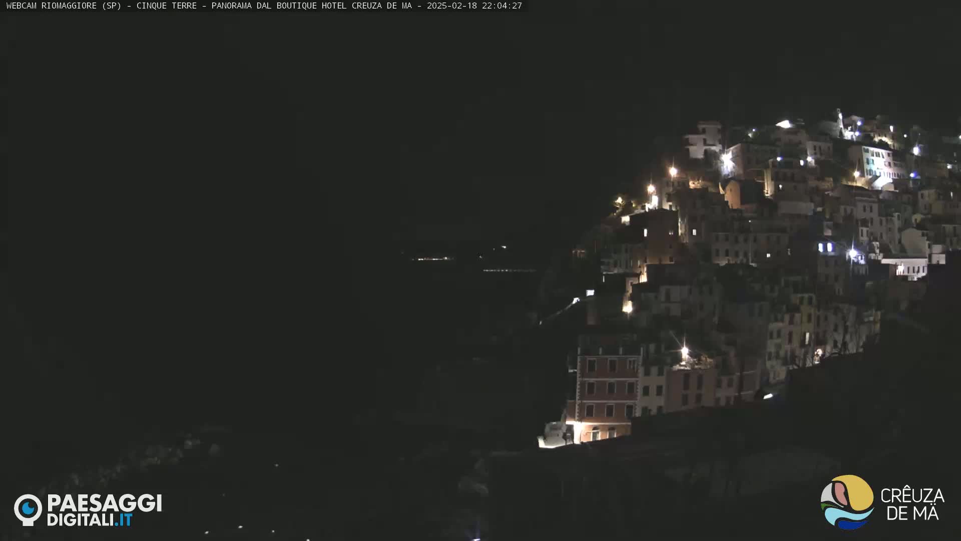 A nighttime view of a hillside town illuminated by scattered lights.