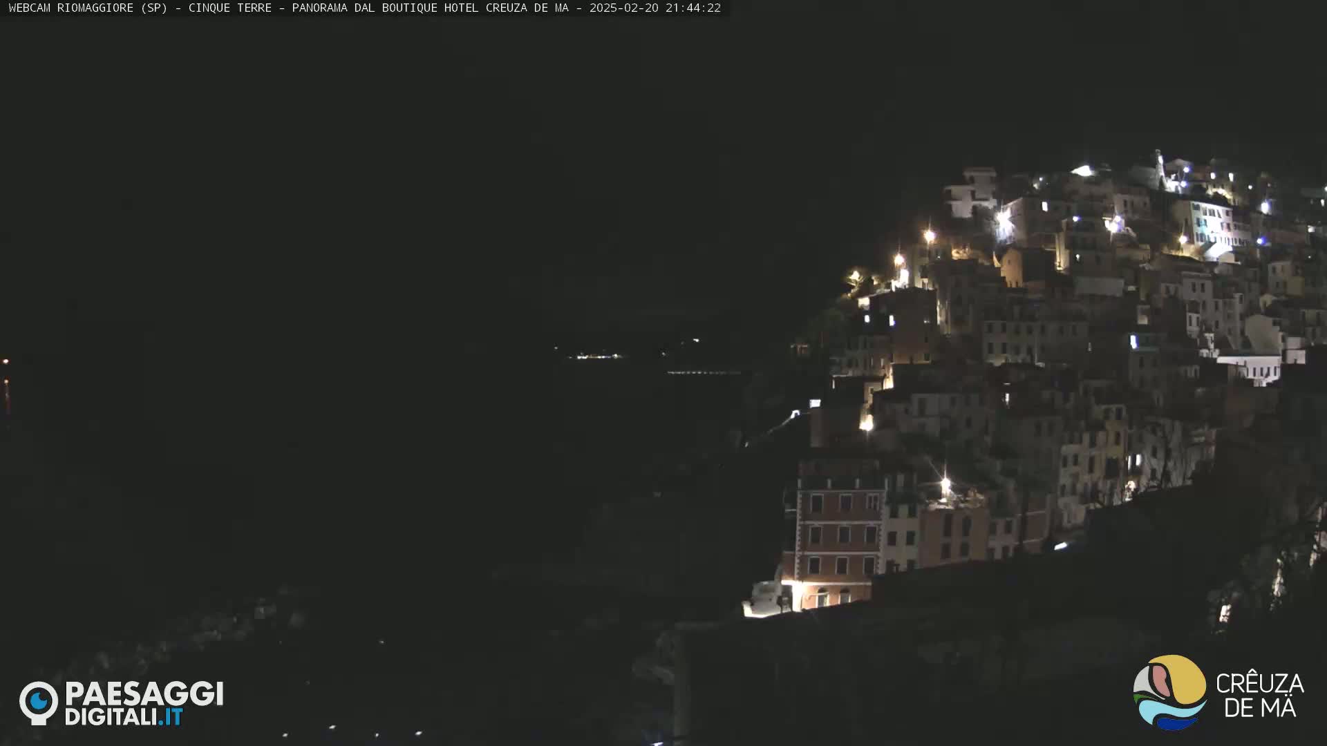 A hillside village is illuminated at night under a dark sky.