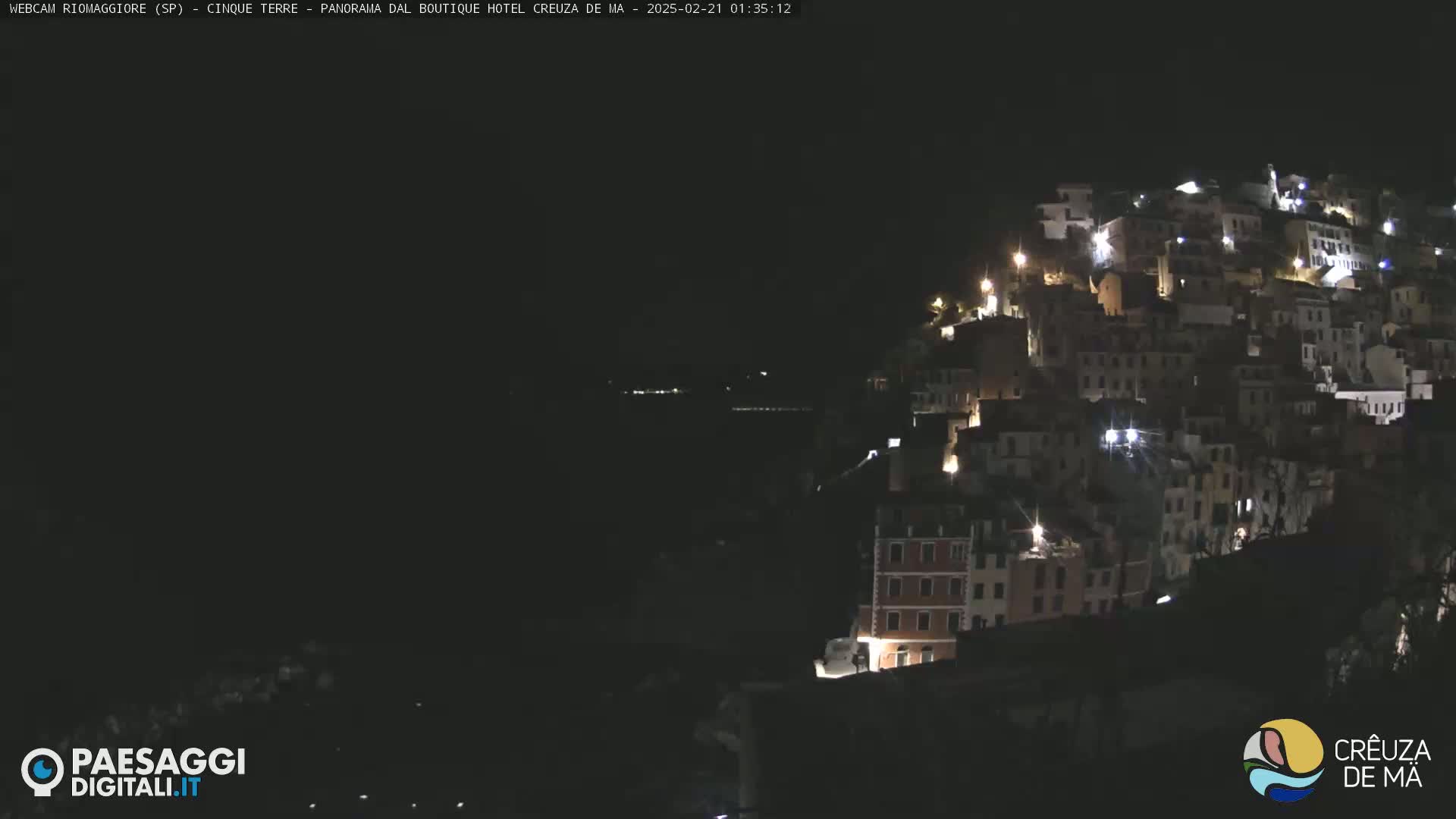 A hillside village is illuminated at night.