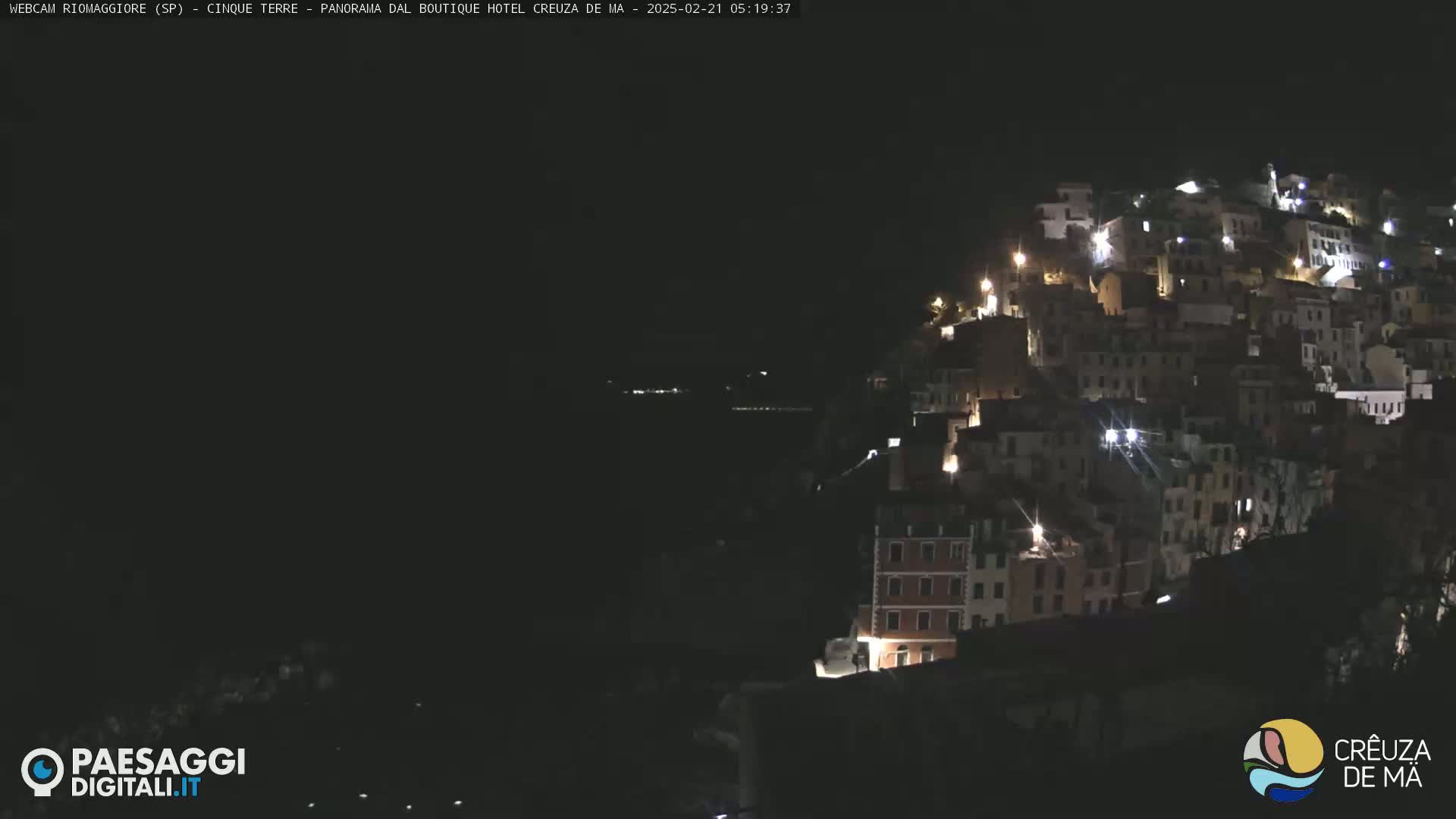A nighttime view of a hillside town illuminated by numerous lights.